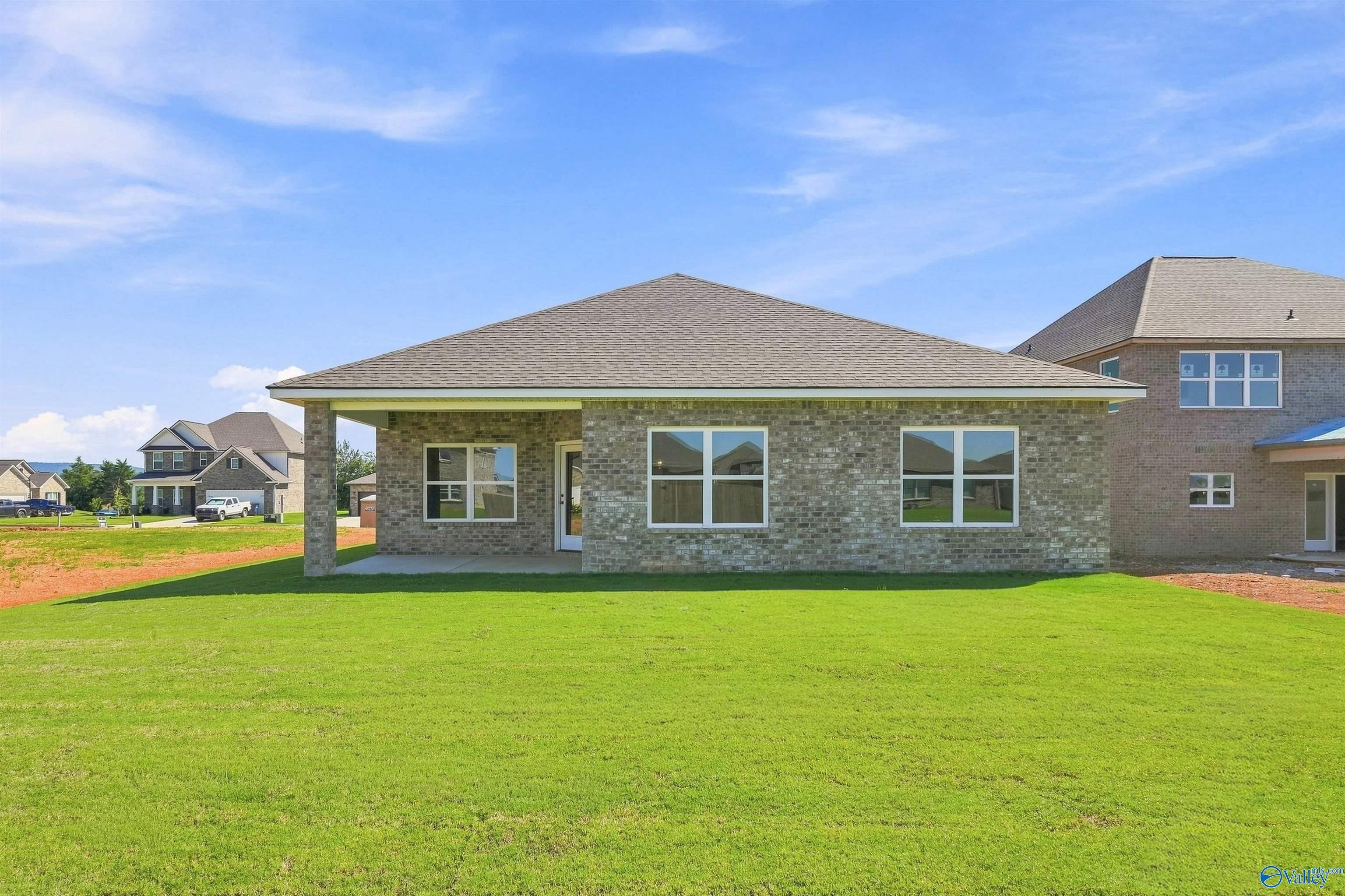 Rear exterior of brick 1-story Davidson Homes Everett B with covered patio and large backyard in Ivy Hills, Toney, Alabama