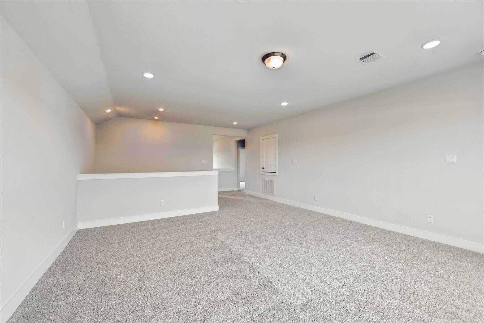 Spacious upstairs loft with gray carpet, recessed lights, and balcony overlook in Davidson Homes The Philip A, Lago Mar, Texas City