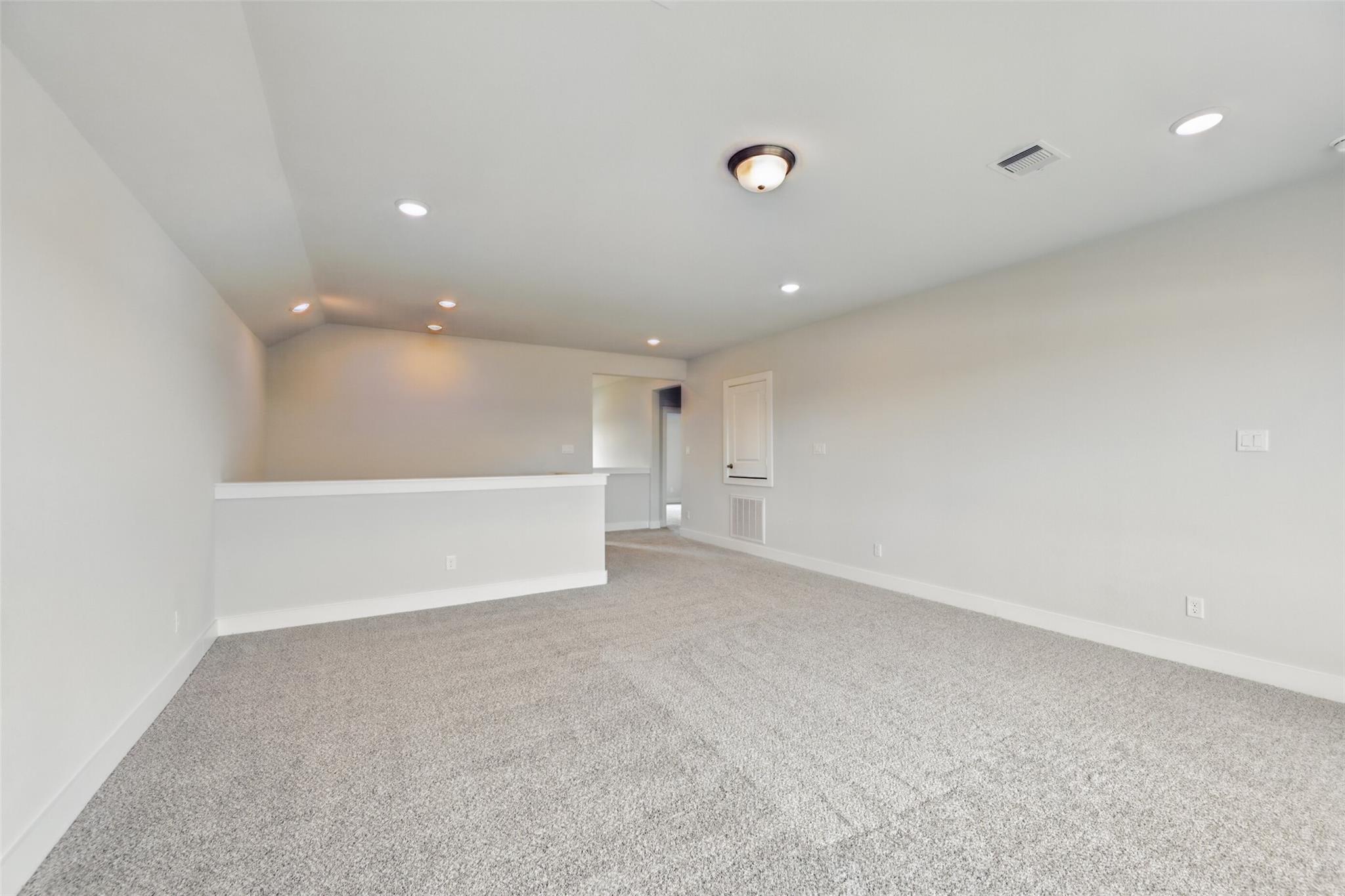 Spacious upstairs loft with gray carpet, recessed lights, and balcony overlook in Davidson Homes The Philip A, Lago Mar, Texas City