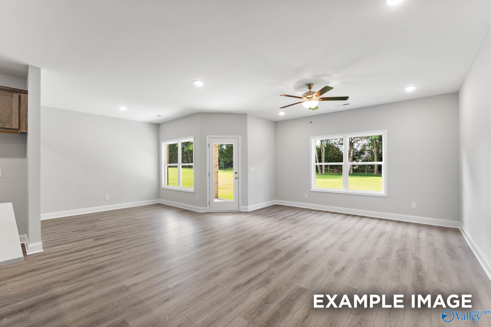 Bright open living room with ceiling fan, large windows, French door to lush backyard in 4-bedroom Davidson Homes The Daphne C, Arab, Alabama