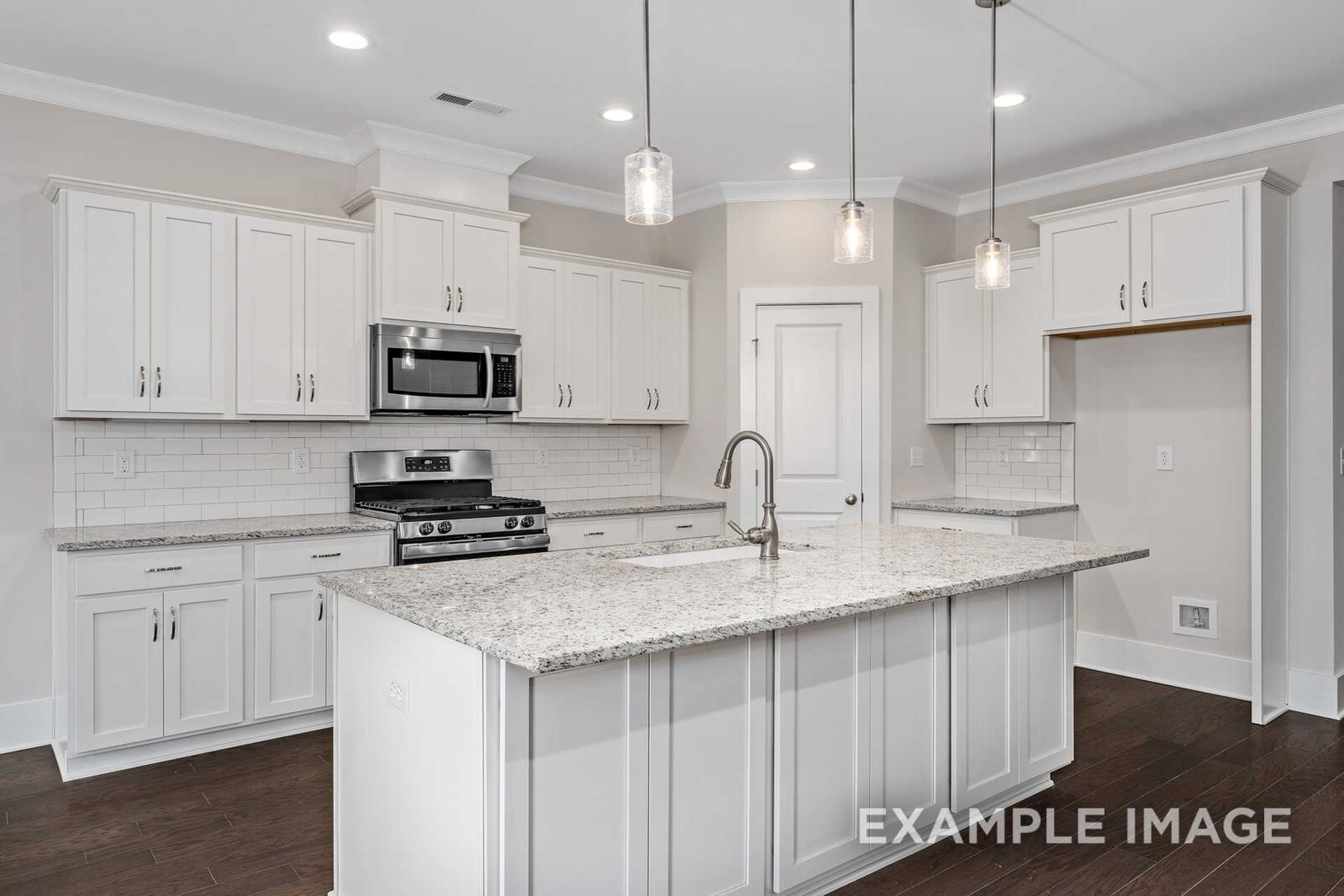 Spacious kitchen in The Rockford home with white shaker cabinets, quartz island, stainless appliances, subway tile backsplash