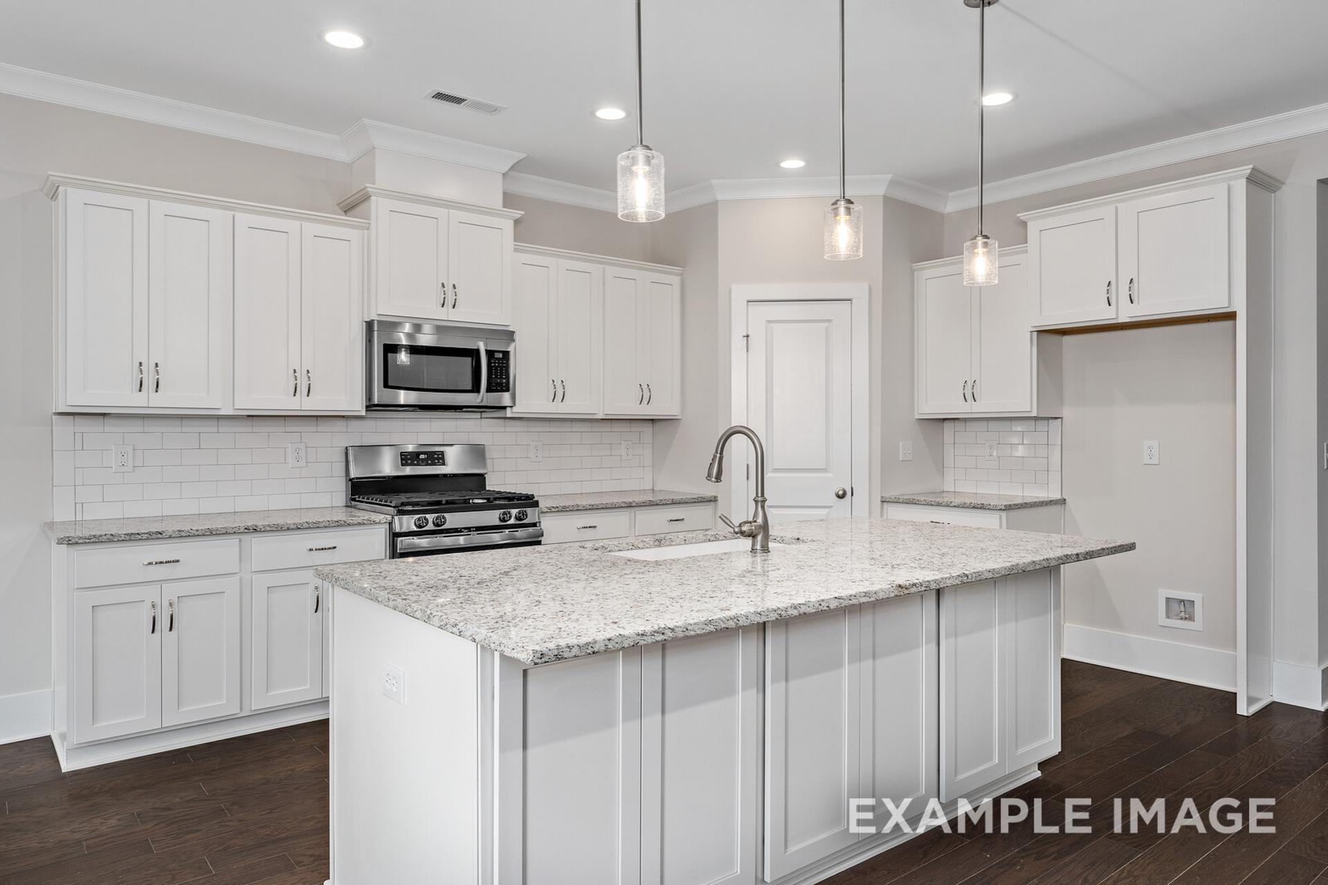 Spacious gourmet kitchen in The Rockford home with white shaker cabinets, granite island, subway tile backsplash, and stainless appliances