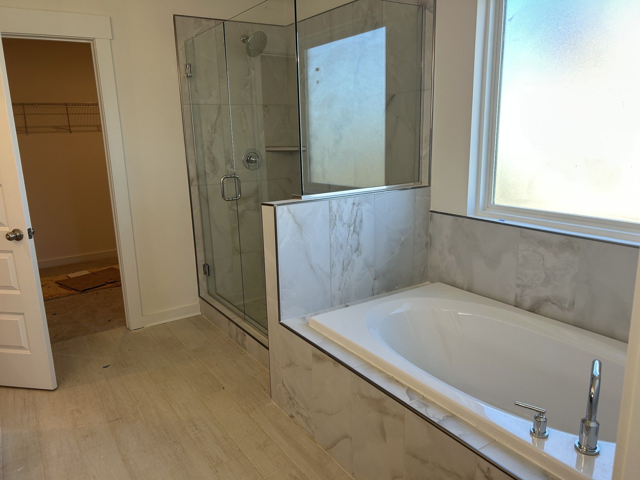 Luxurious master bathroom featuring freestanding tub, frameless glass shower, and marble-look tiles in Davidson Homes The Henry C, Mt. Juliet