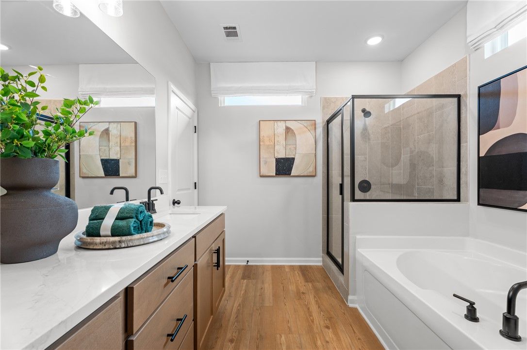 Modern primary bathroom with dual vanity, soaking tub, and walk-in shower in Davidson Homes Stella B plan, Opelika, Alabama