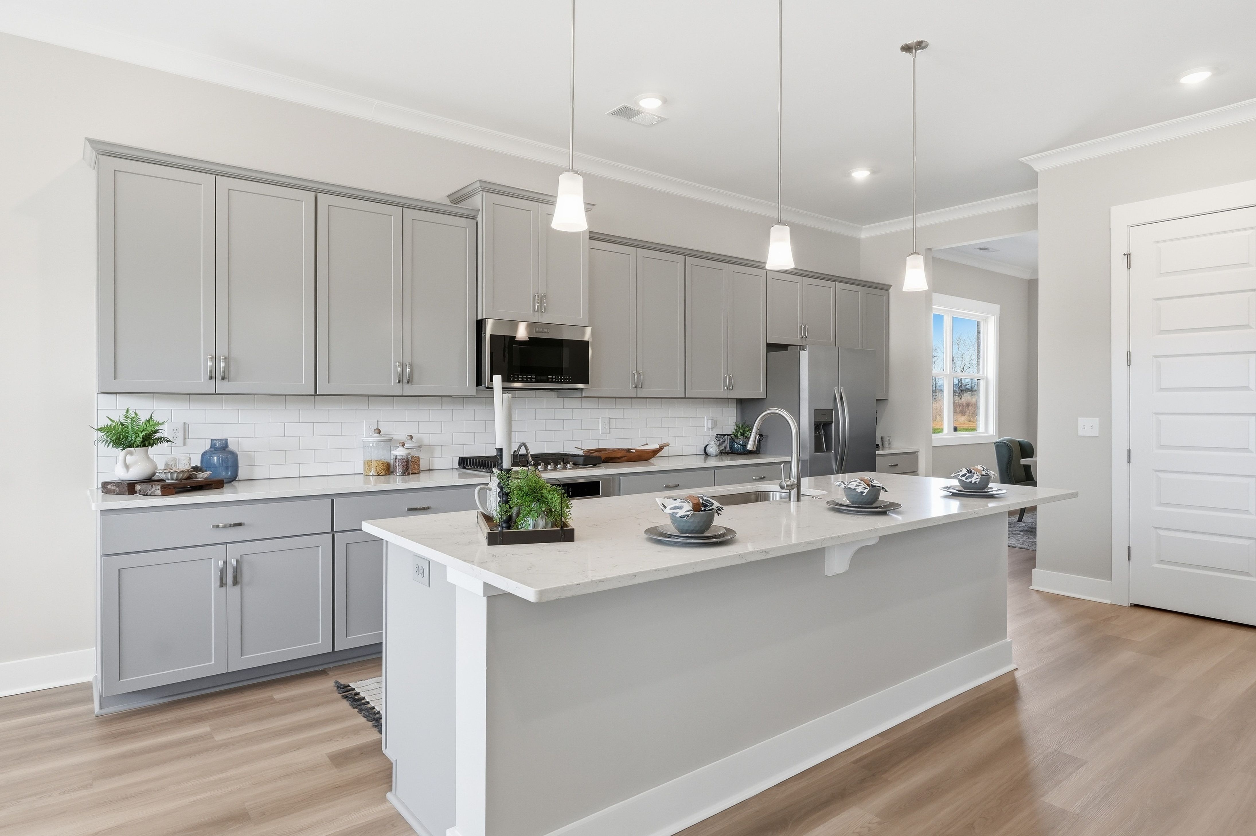 Contemporary kitchen with gray shaker cabinets, white quartz island, stainless appliances at The Meadows at Hampton Cove, Owens Cross Roads AL
