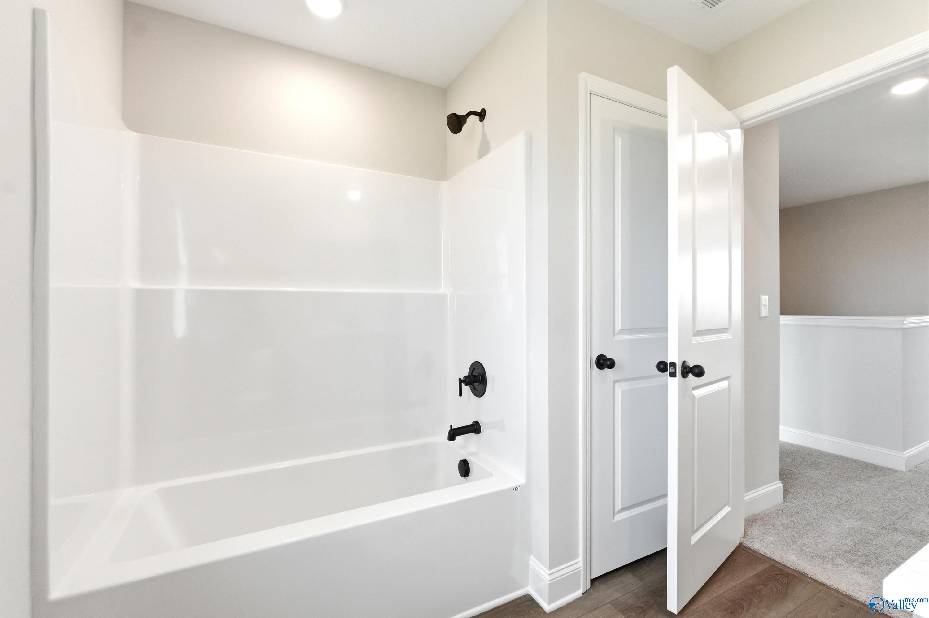 Modern bathroom with white tub surround and matte black fixtures in a Davidson Homes Shelby A floor plan, Hazel Green, AL.