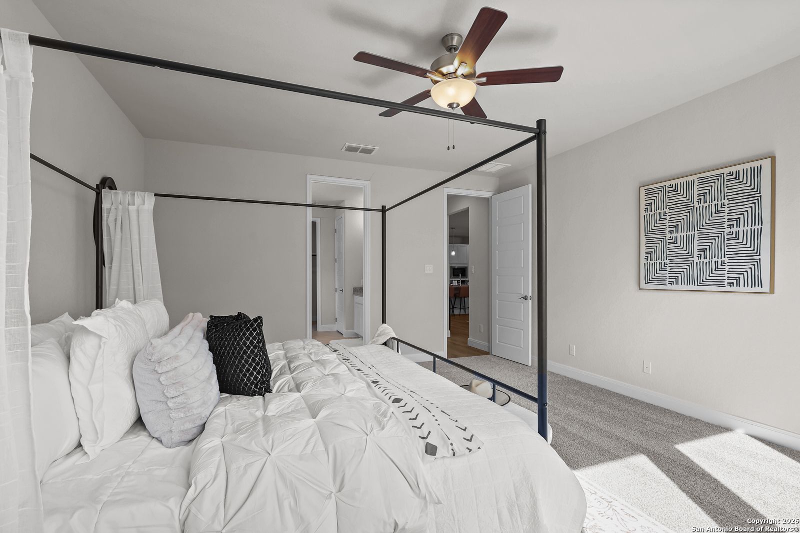 Elegant canopy bed with tufted white bedding and ceiling fan in master bedroom of Davidson Homes The Lanier H, Ladera San Antonio