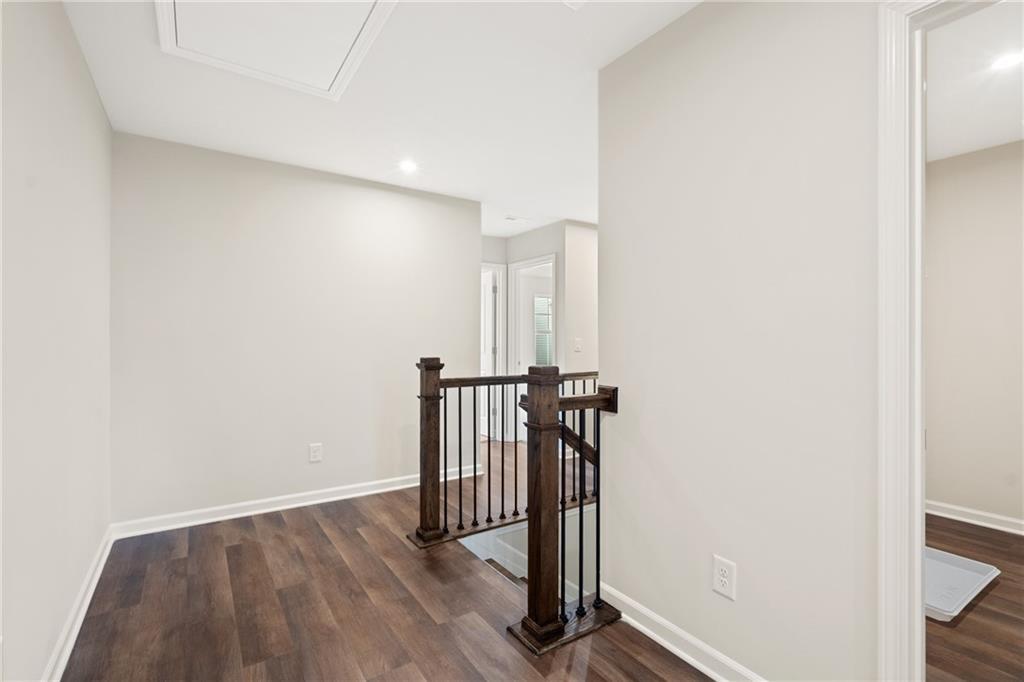 Spacious upstairs hallway with wooden staircase railing and light gray walls in Davidson Homes The Cary B, Kennesaw, Georgia