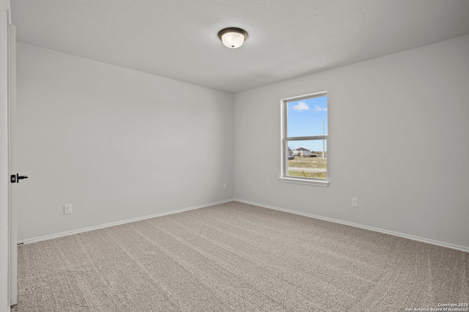 Bright secondary bedroom with neutral walls, beige carpet, and window view in Davidson Homes The Douglas C, Seguin, Texas