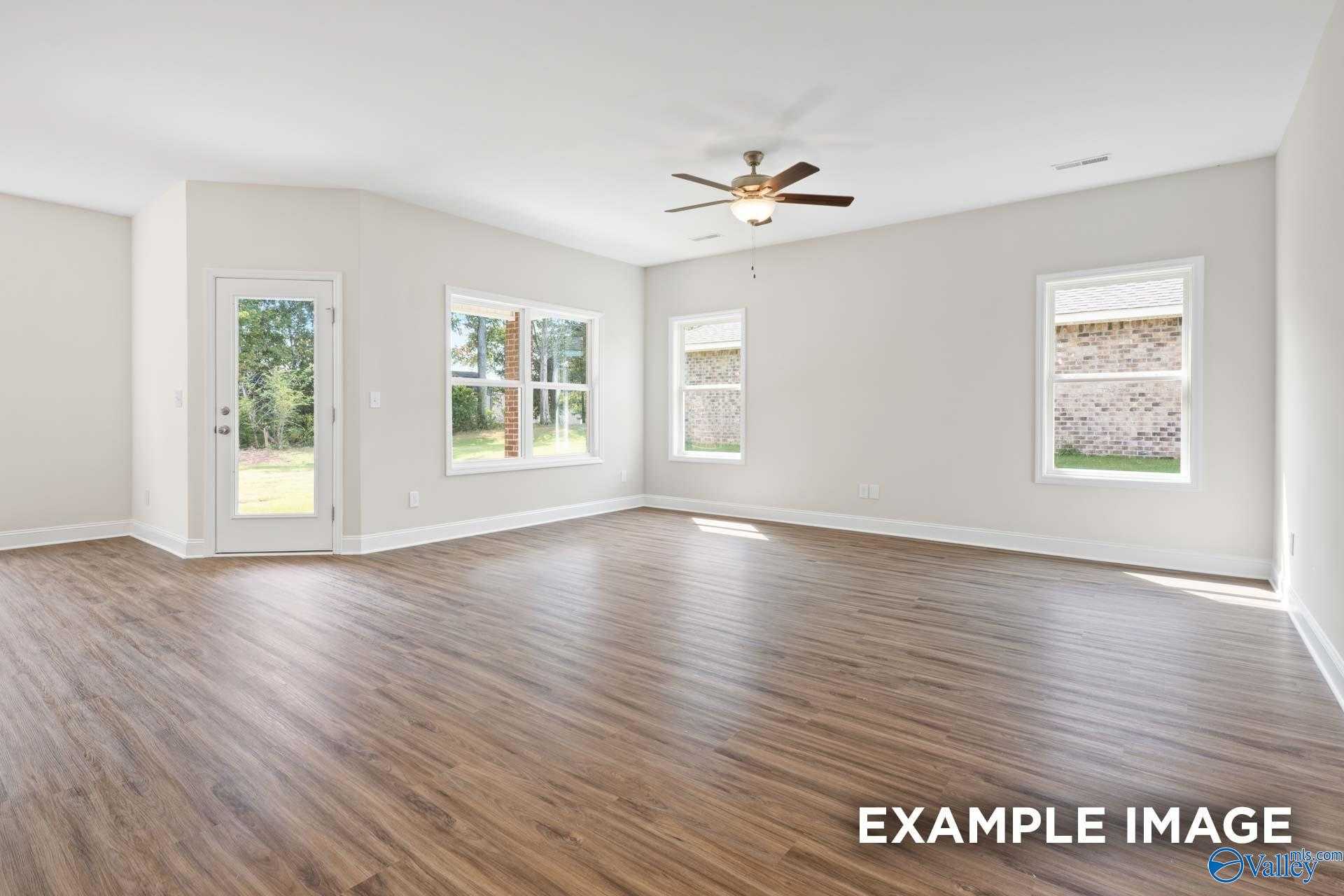 Bright living room with large windows, French doors to backyard, and ceiling fan in The Franklin 3-bedroom home, Meridianville, Alabama