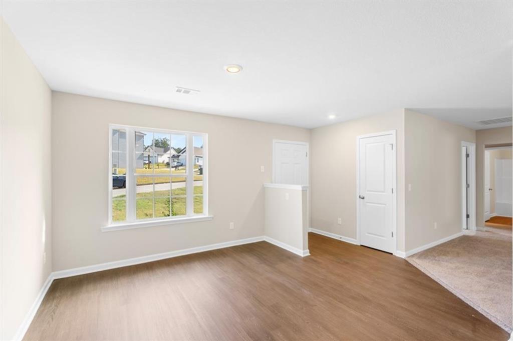 Bright secondary bedroom with large window overlooking green lawn, beige walls, wood floors in Davidson Homes The Washington, Phenix City