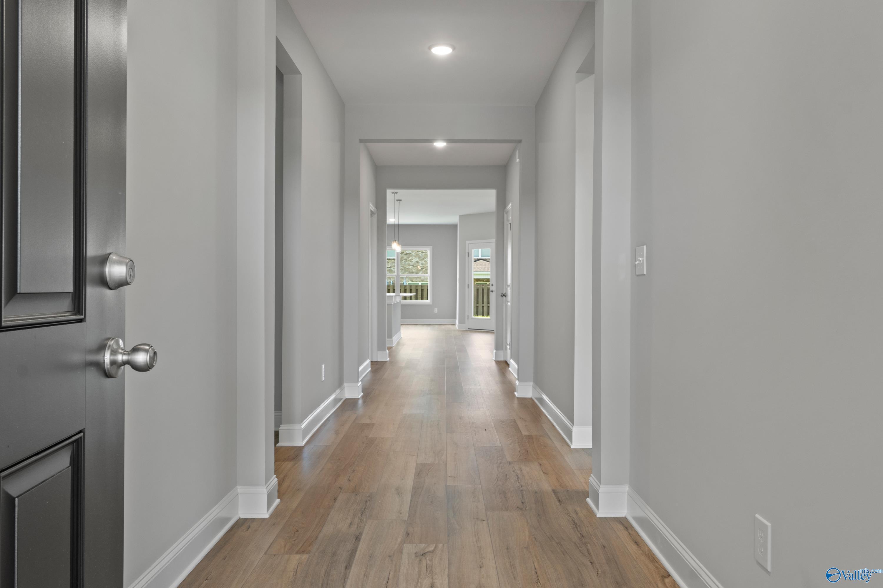 Spacious hallway with light gray walls, hardwood floors, and side doors in Davidson Homes The Everett B, Ivy Hills, Toney, Alabama