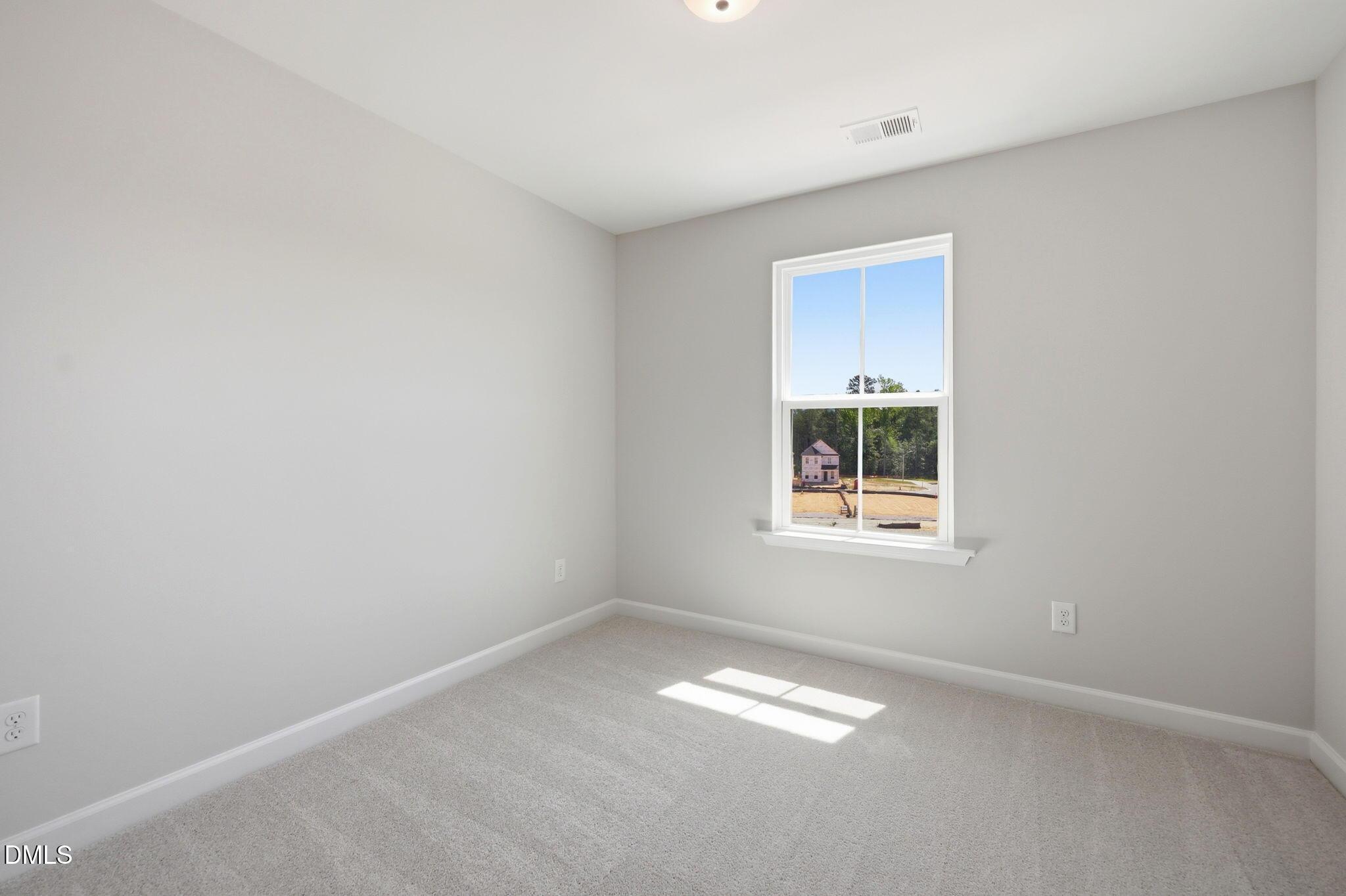 Bright bedroom with neutral carpet in The Avery floor plan at Forestville Yard Townhomes in Knightdale, North Carolina.