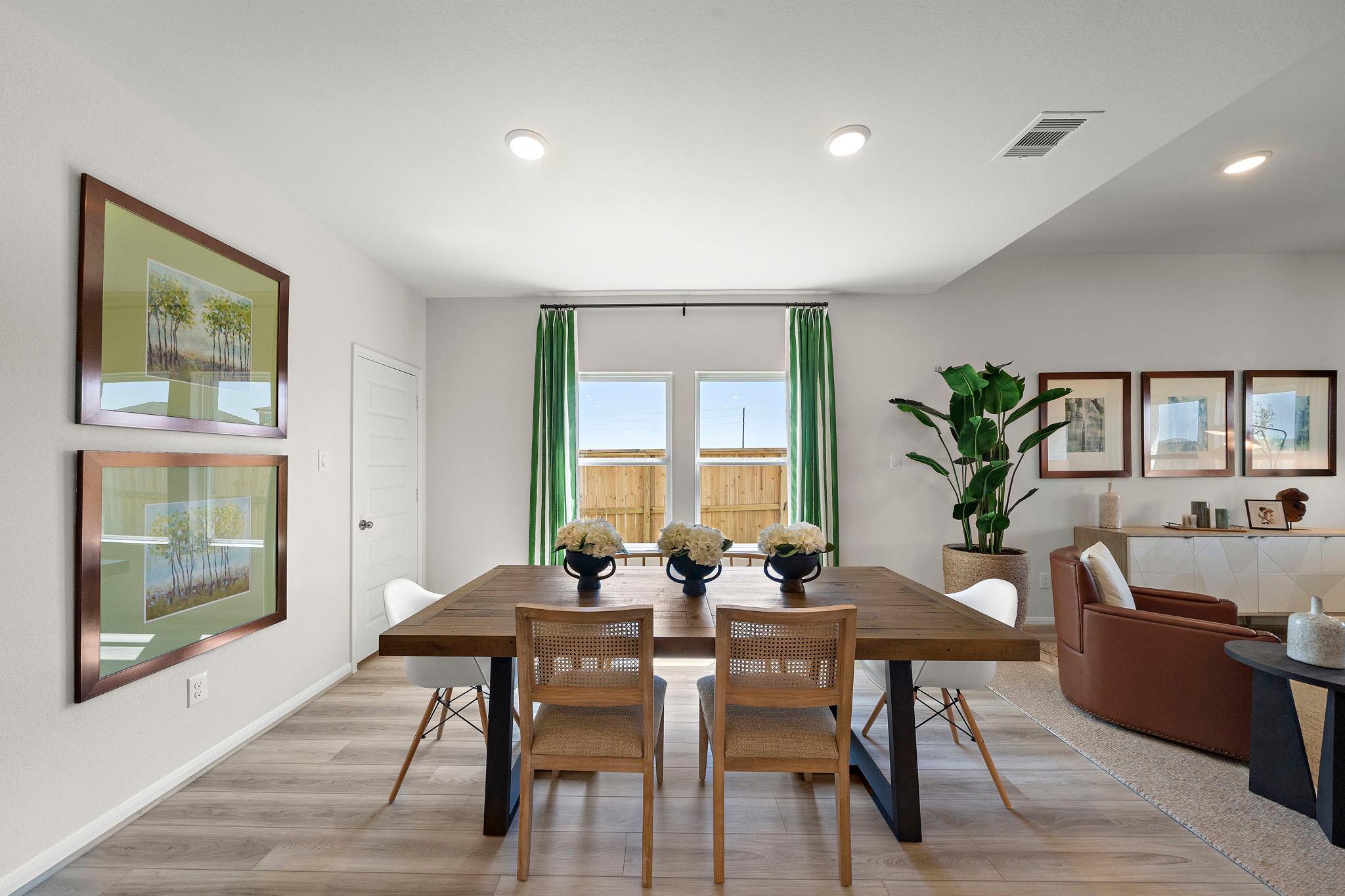 Spacious dining room at River Ranch Meadows in Dayton Texas with wooden table, floral centerpiece, green curtains, and potted plant