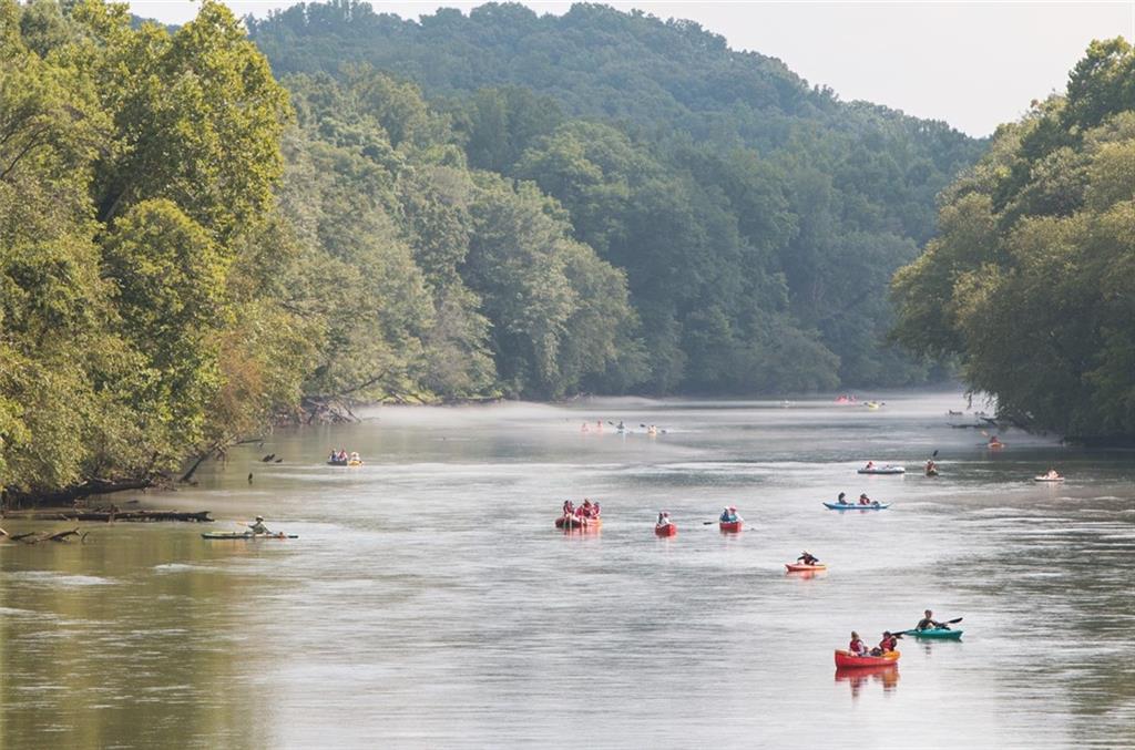 Kayakers and canoers paddling serene river amid lush green trees and hills near The Village at Shallowford, Kennesaw, Georgia