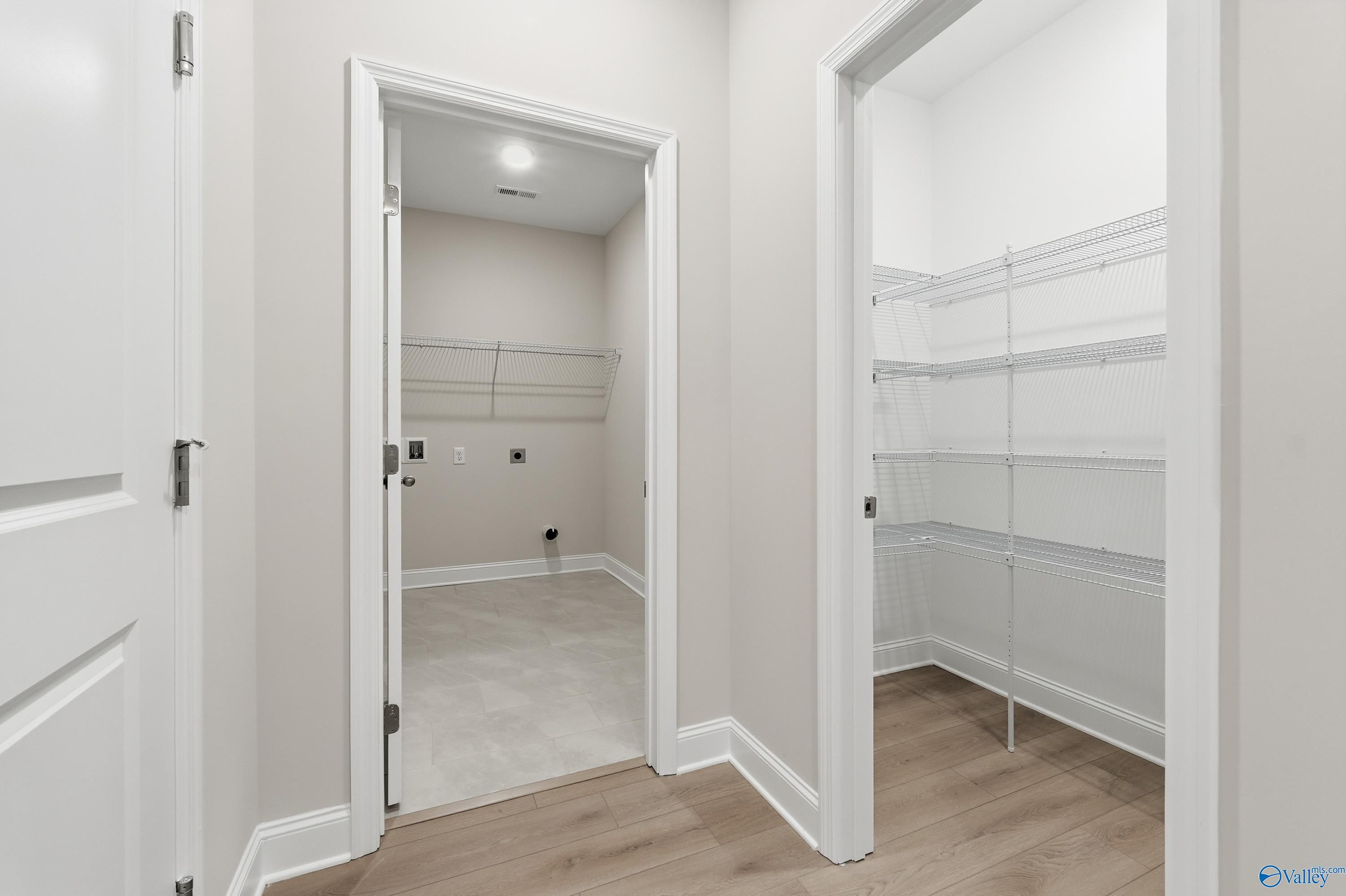 Bright laundry room with washer/dryer hookups, tiled floor and adjacent pantry shelving in Davidson Homes The Kirkland, Decatur AL