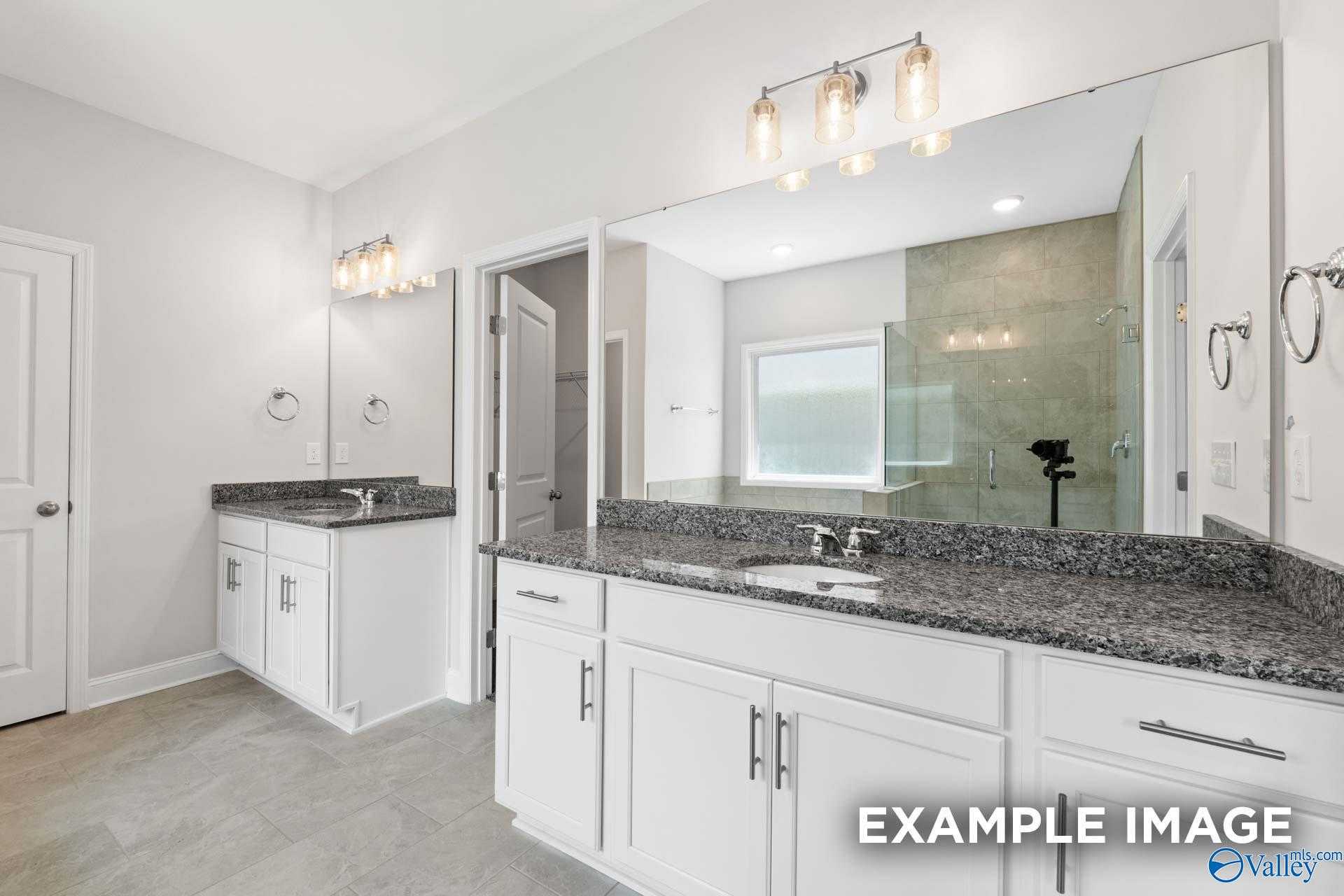 Modern double vanity with granite countertops, large mirrors, and tiled shower in The Lanier master bath by Davidson Homes, Meridianville, AL