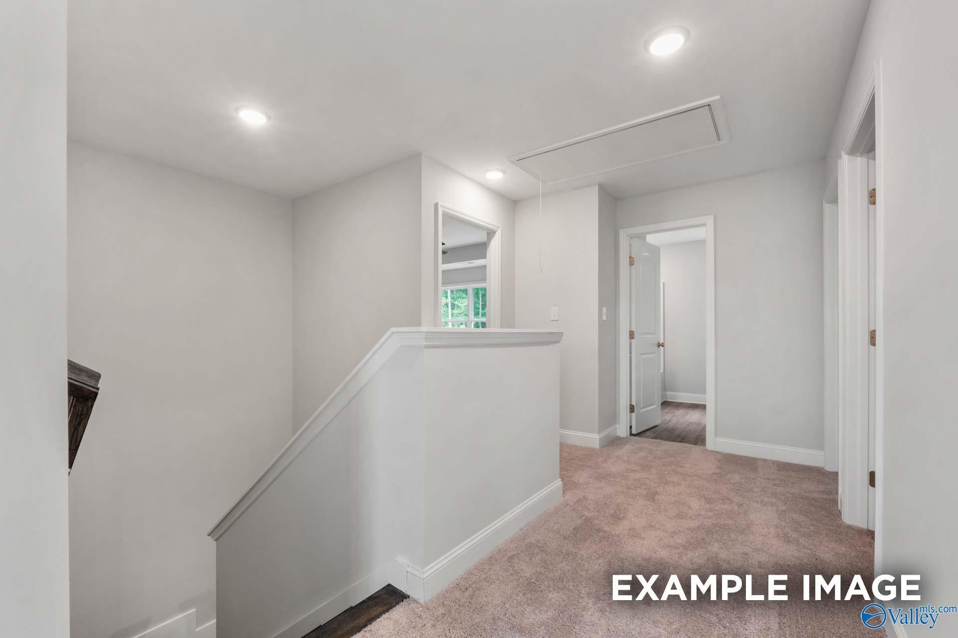 Bright upstairs hallway with white walls, beige carpet, recessed lights, and bedroom doors in The Shelby C floor plan, Arab, Alabama
