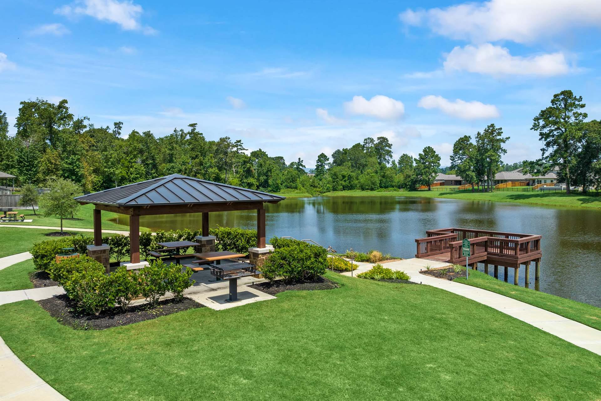 Scenic wooden gazebo with picnic tables by serene lake and dock at Lakes at Black Oak in Magnolia, Texas