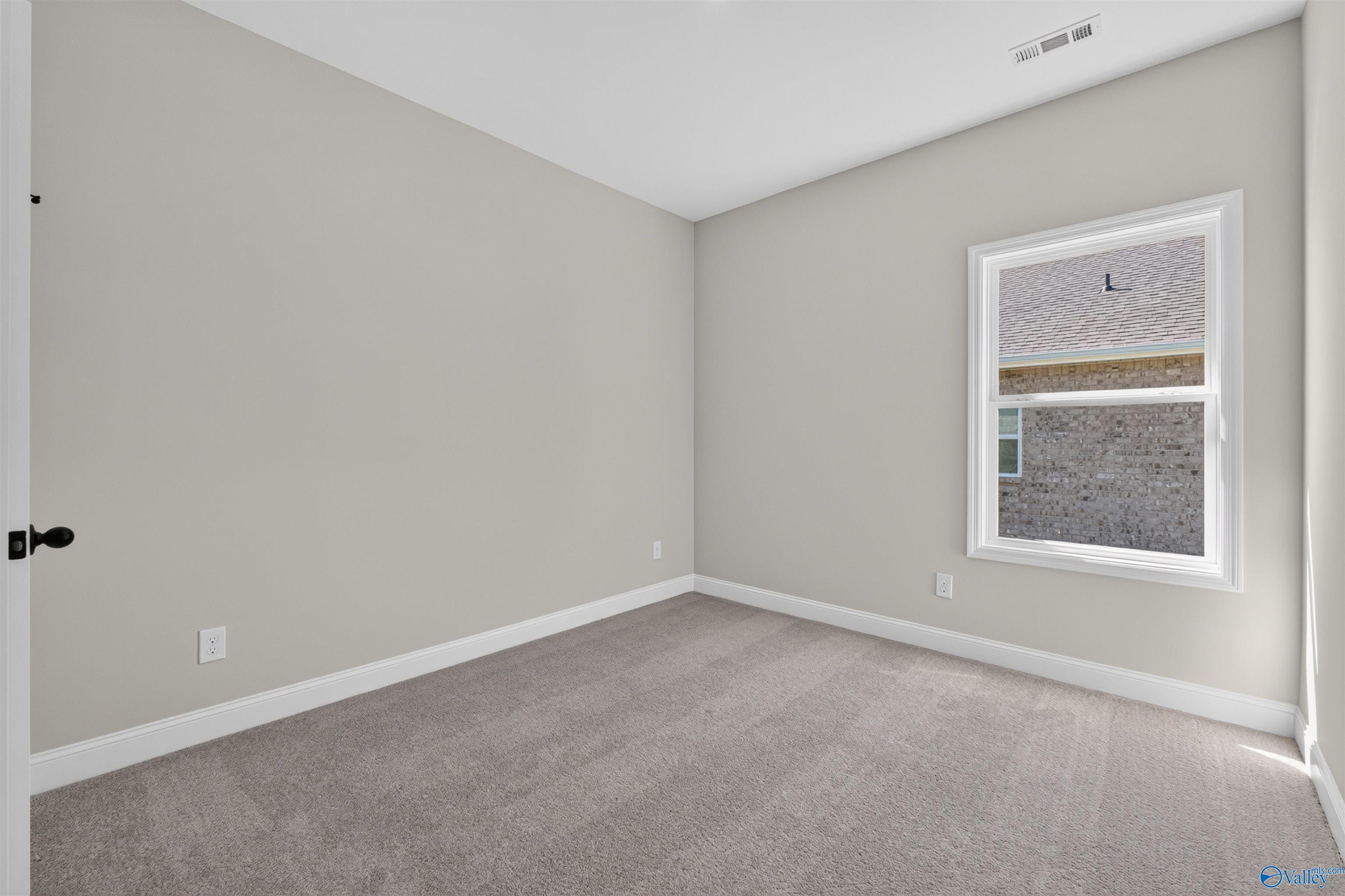 Bright carpeted bedroom with neutral walls and double-pane window in Davidson Homes The Butler floor plan, Hazel Green, Alabama