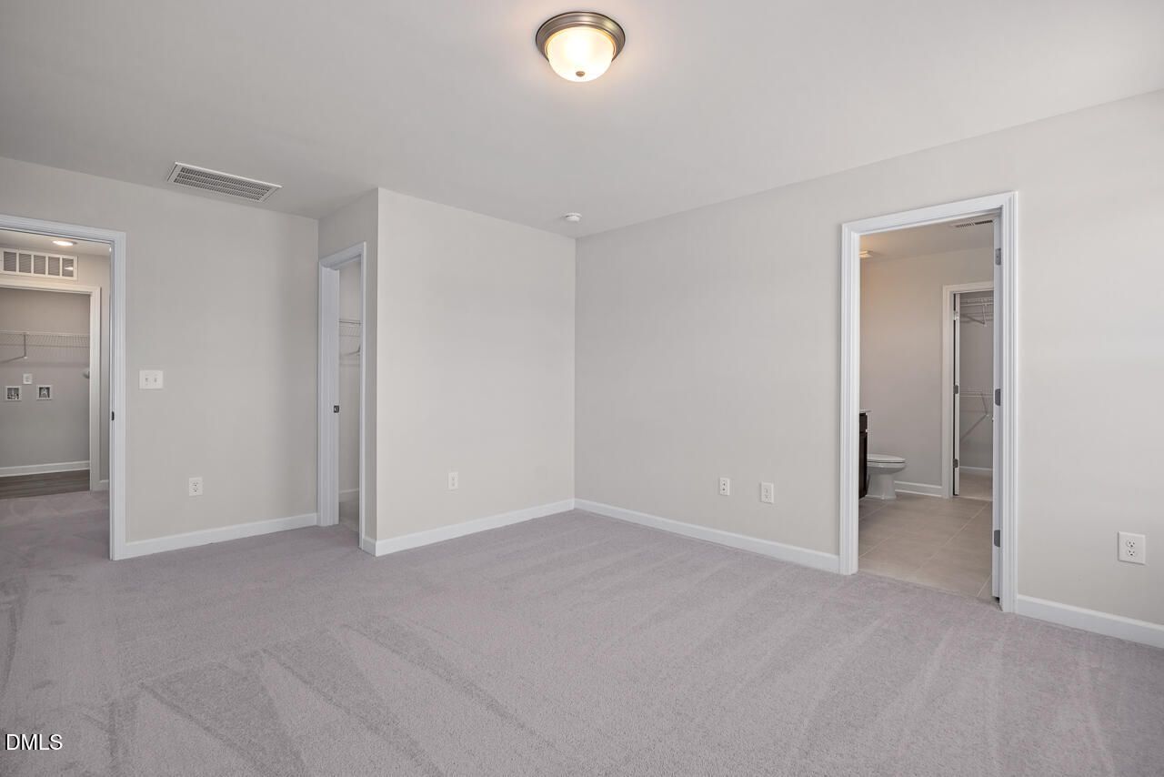 Spacious bedroom with plush carpet and access to walk-in closet in The Grace C floor plan at Retreat at North Main.