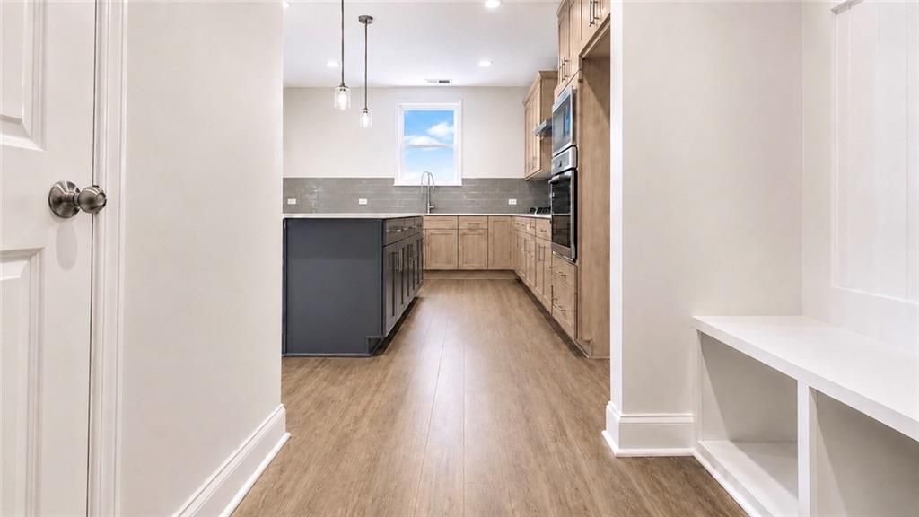 Modern kitchen with dark island and light wood cabinets in The Hickory C floor plan at Wehunt Meadows in Hoschton, Georgia.