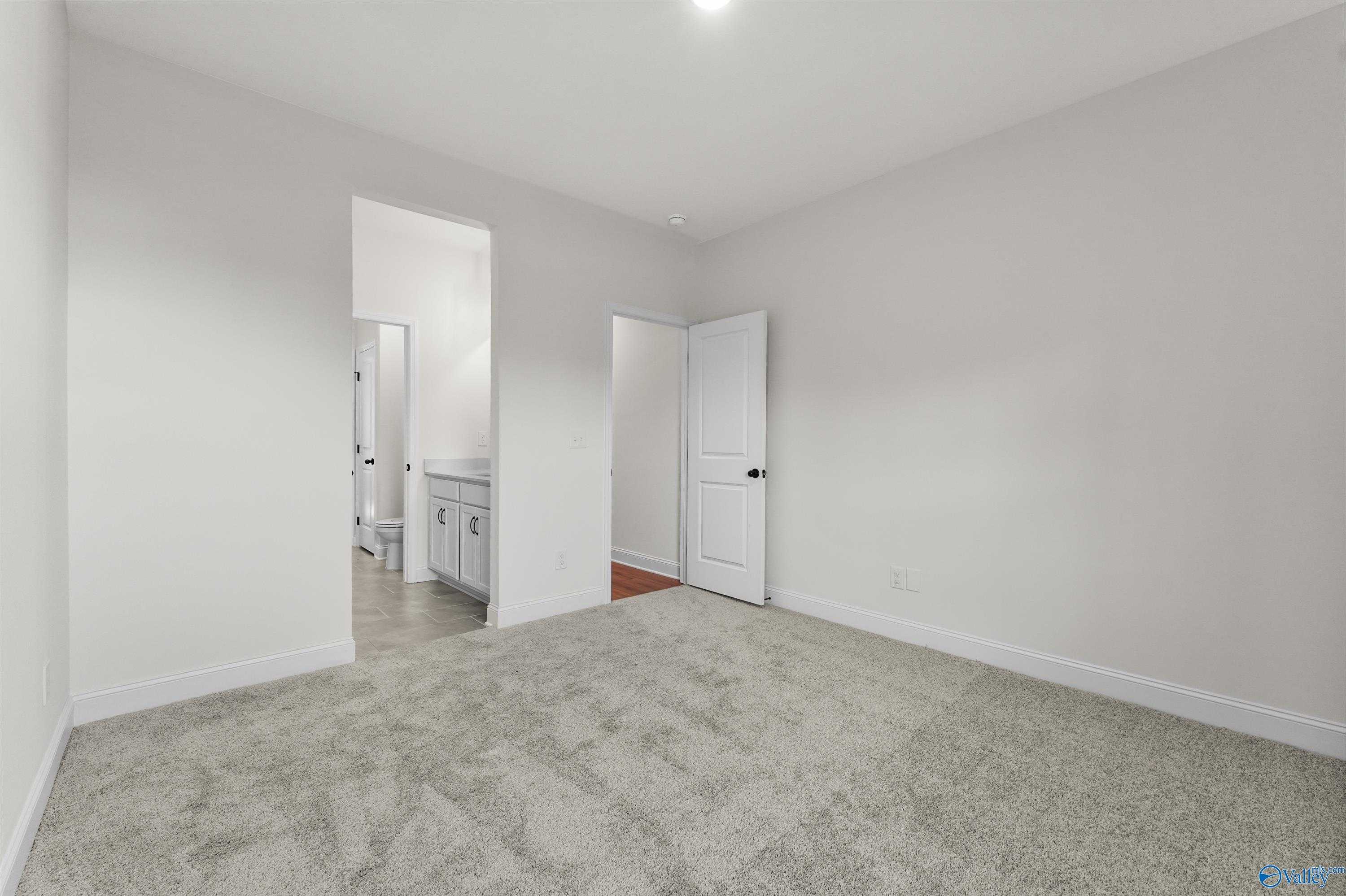 Spacious secondary bedroom with gray carpet and attached bath featuring white vanity in Davidson Homes The Finleigh, Harvest AL