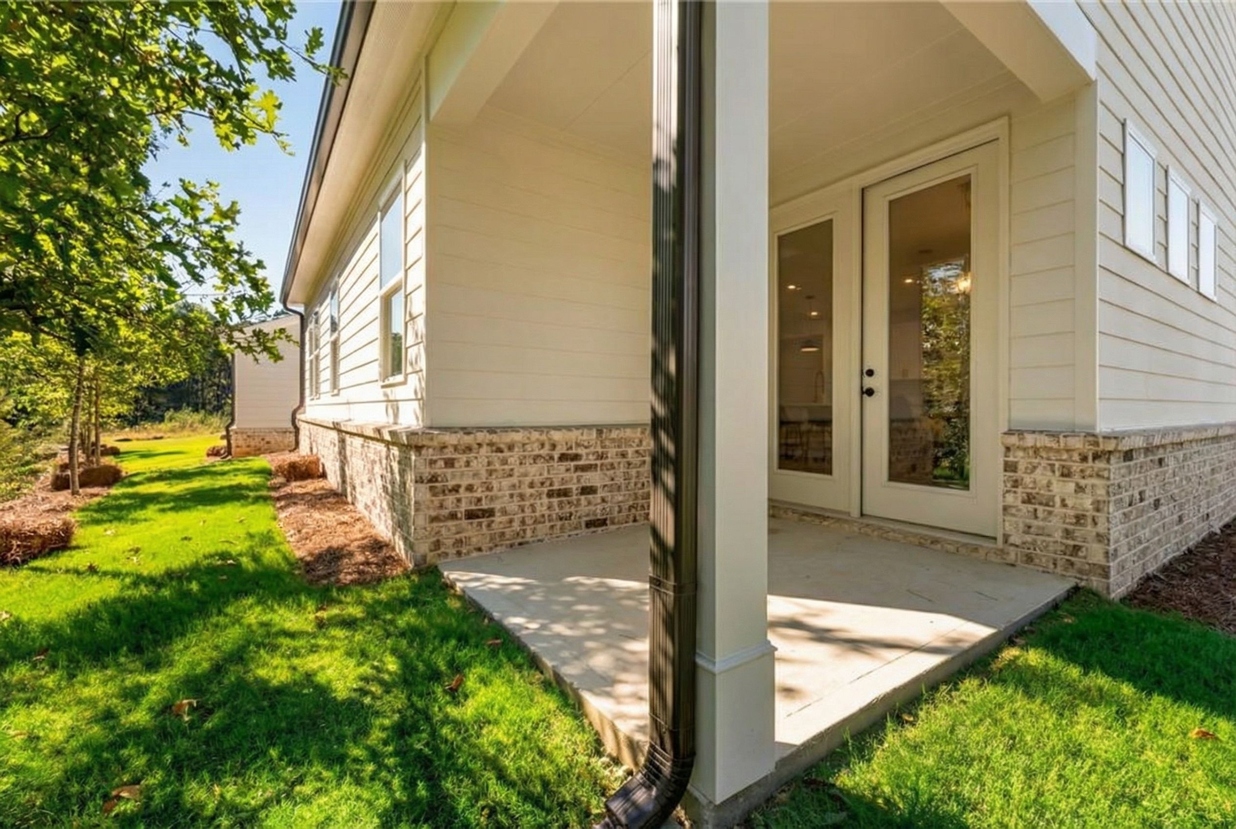 Covered back patio with French doors on white brick-accented home exterior, Davidson Homes The Daphne B, Kelly Preserve, Loganville, Georgia