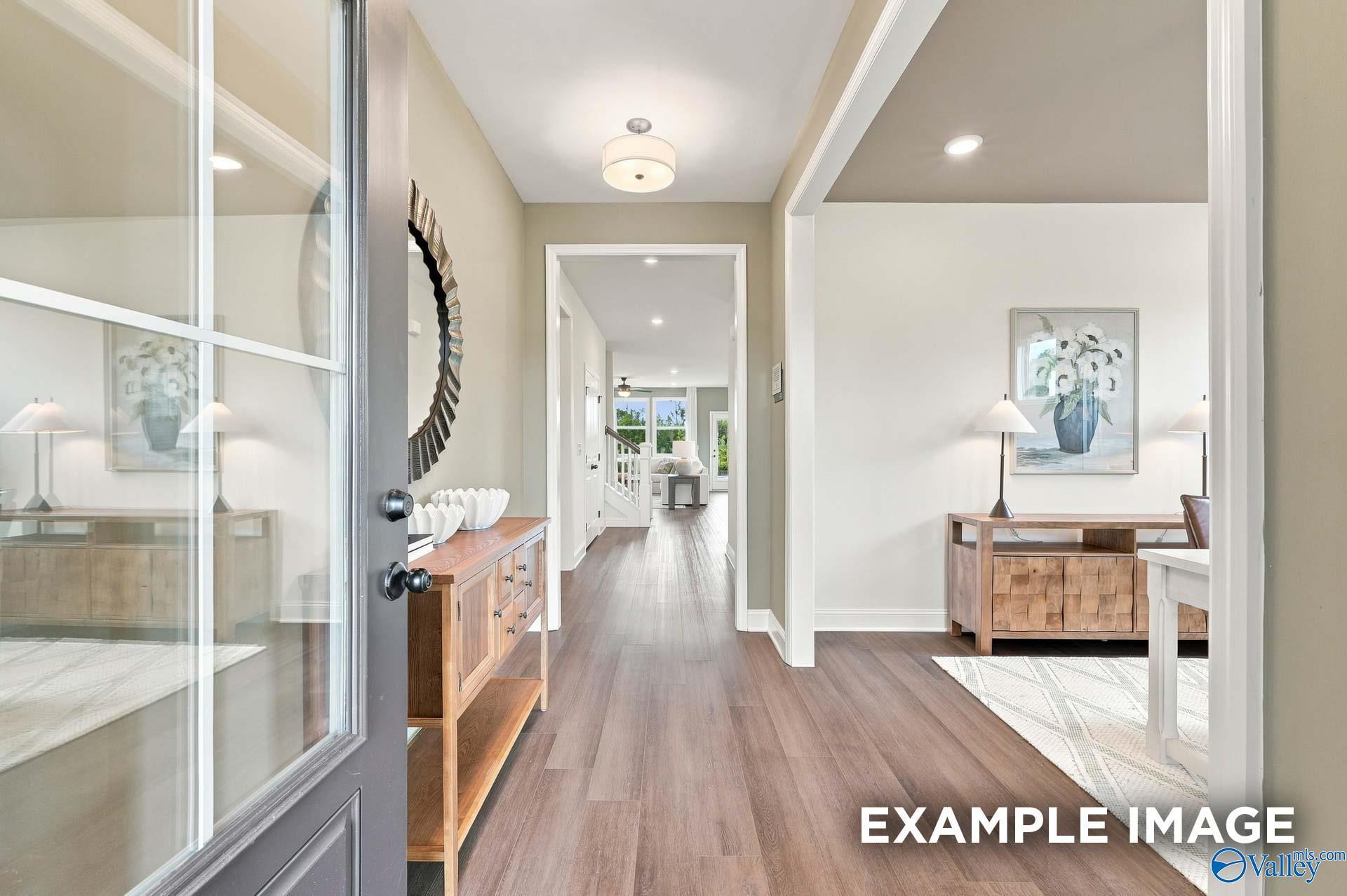 Bright welcoming foyer with glass-paneled door, wood console table, and hardwood floors in Davidson Homes The Ashport G plan, Berry Cove