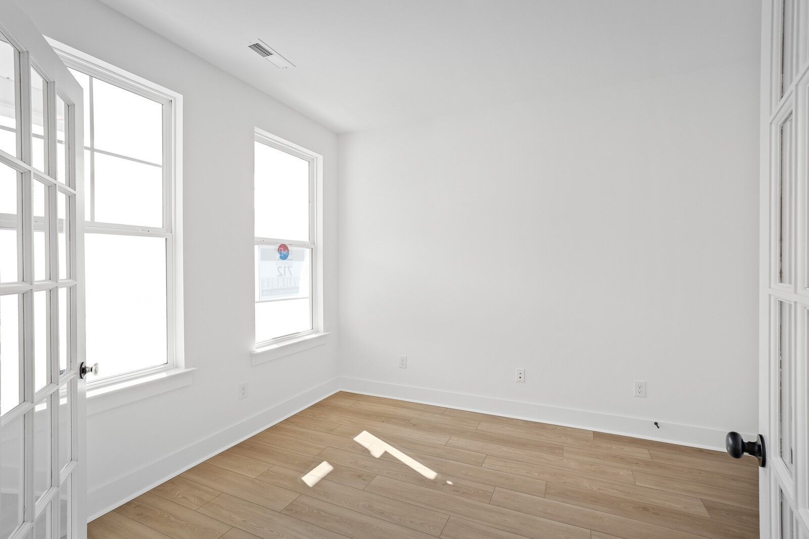 Bright empty bedroom with large windows, French doors, and hardwood floors in Davidson Homes The Logan C, Gallatin, TN