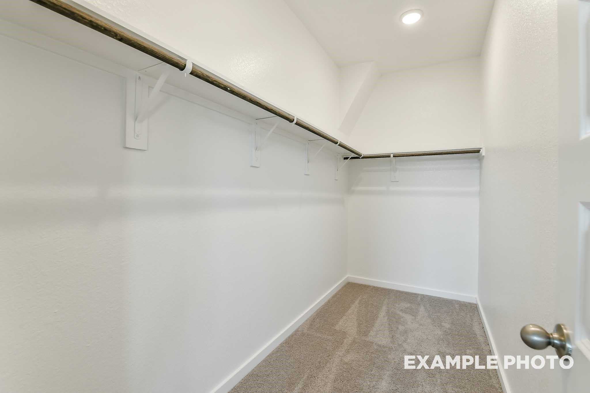 Spacious walk-in closet with wooden hanging rods and shelves in Davidson Homes The Colorado F, Conroe, Texas