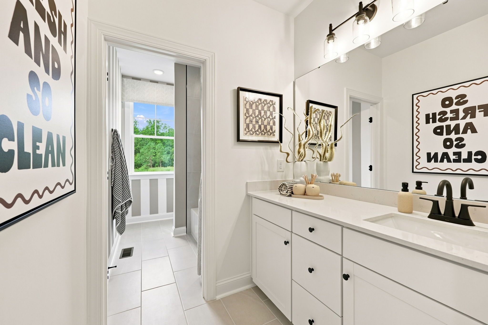 Modern bathroom in The Barrington C home design featuring a white vanity, quartz countertop, and bright tiled flooring.