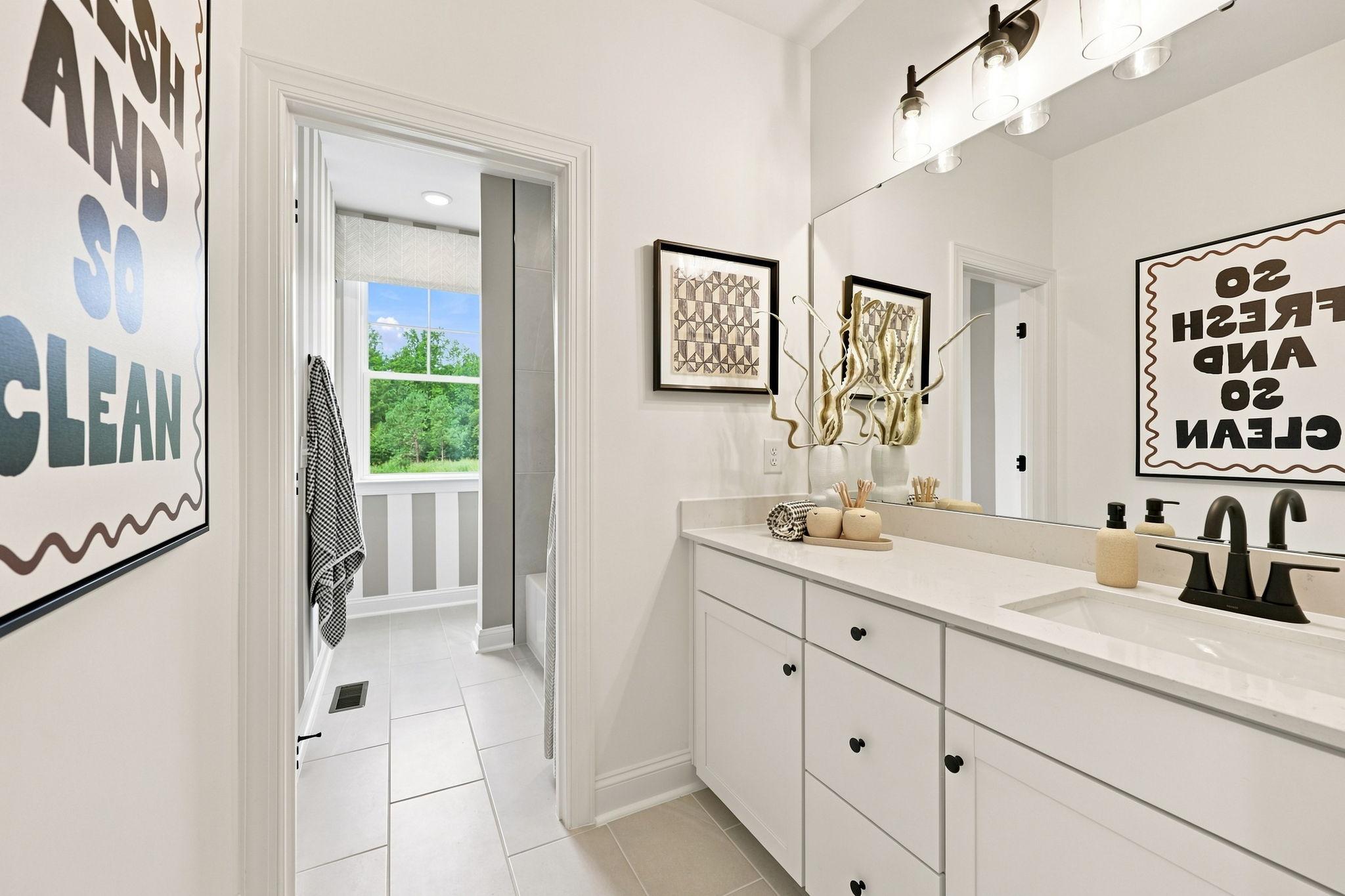 Modern bathroom in The Barrington C home design featuring a white vanity, quartz countertop, and bright tiled flooring.