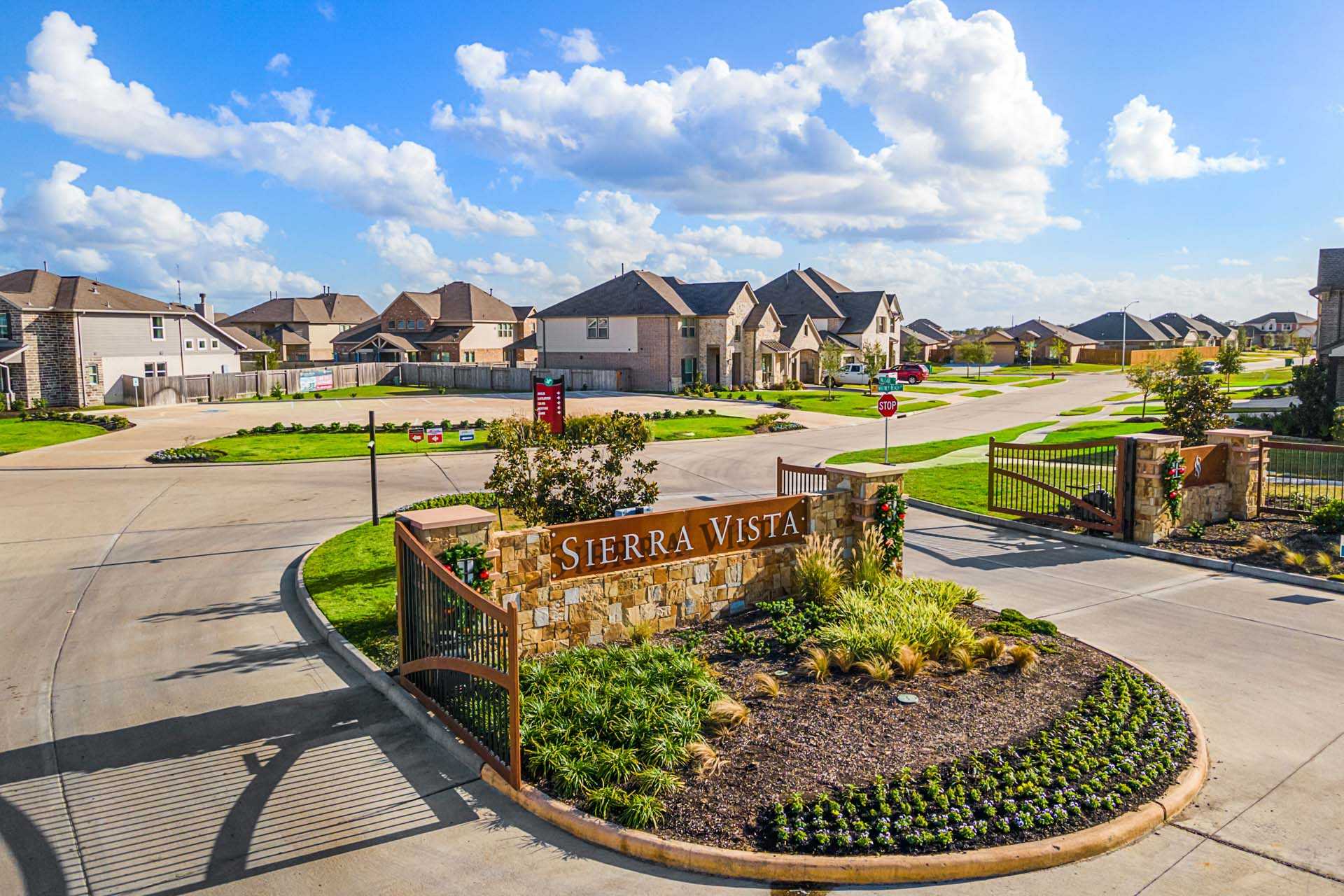 Sierra Vista neighborhood entrance in Rosharon Texas with stone sign, wrought iron gates, lush landscaping and modern homes