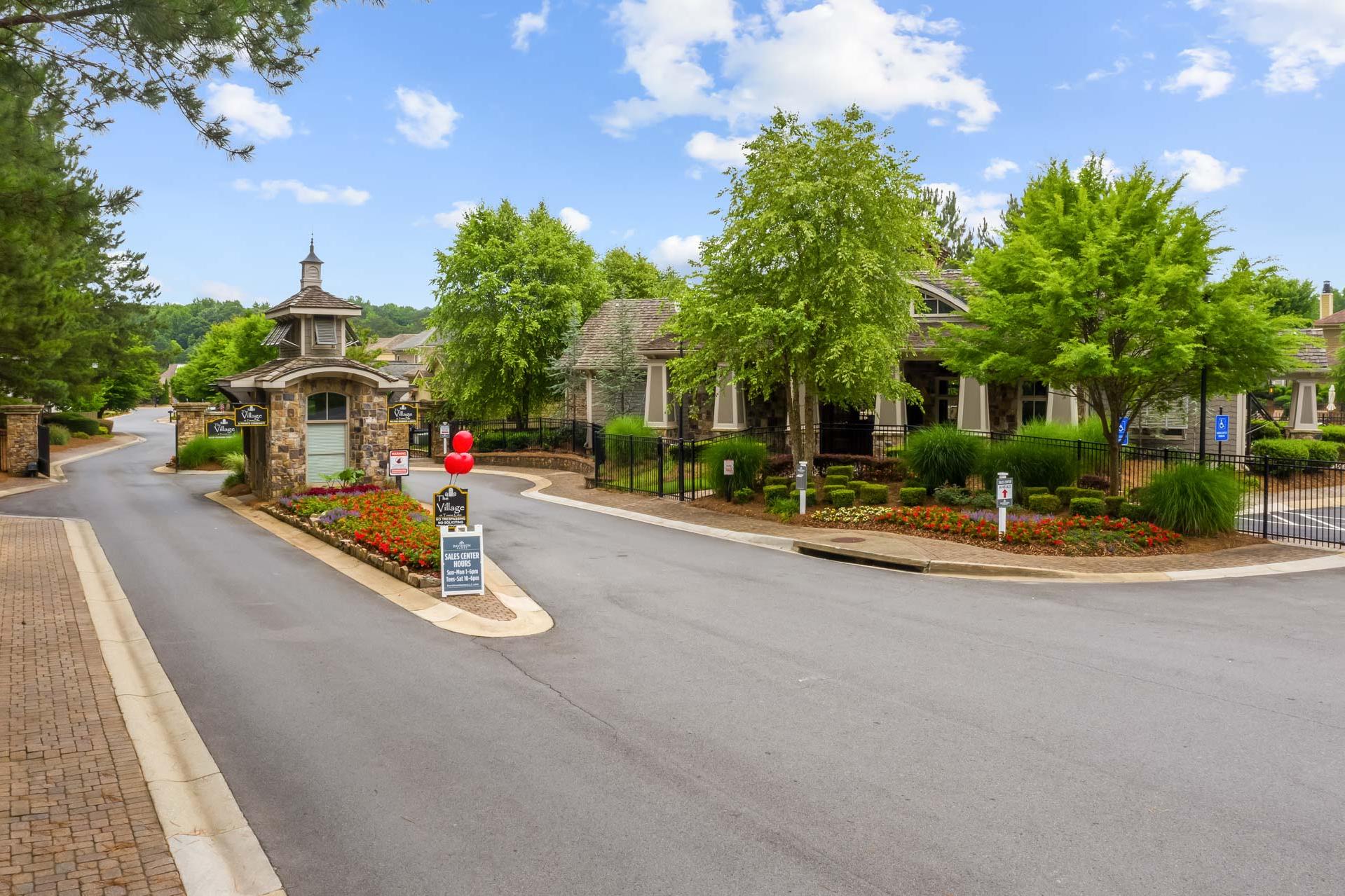 Gated stone entrance at The Village at Towne Lake in Woodstock Georgia with peaked pavilion, flower beds and oak trees
