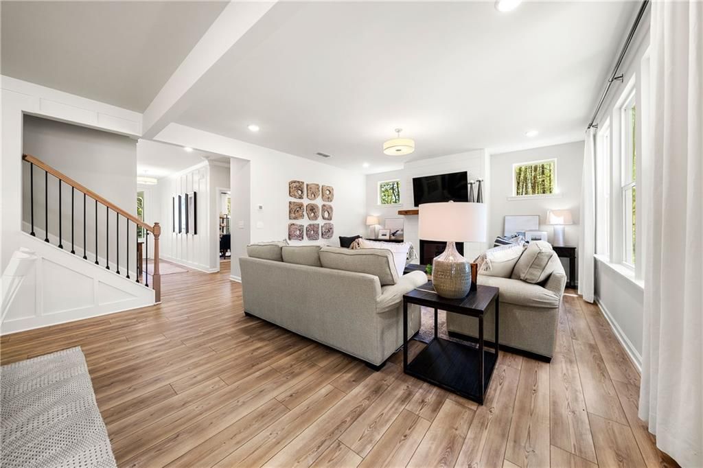 Open-concept living room with beige sofas, wooden coffee table, TV wall, and large windows in Davidson Homes Willow B, Riverwood, Dallas, Georgia