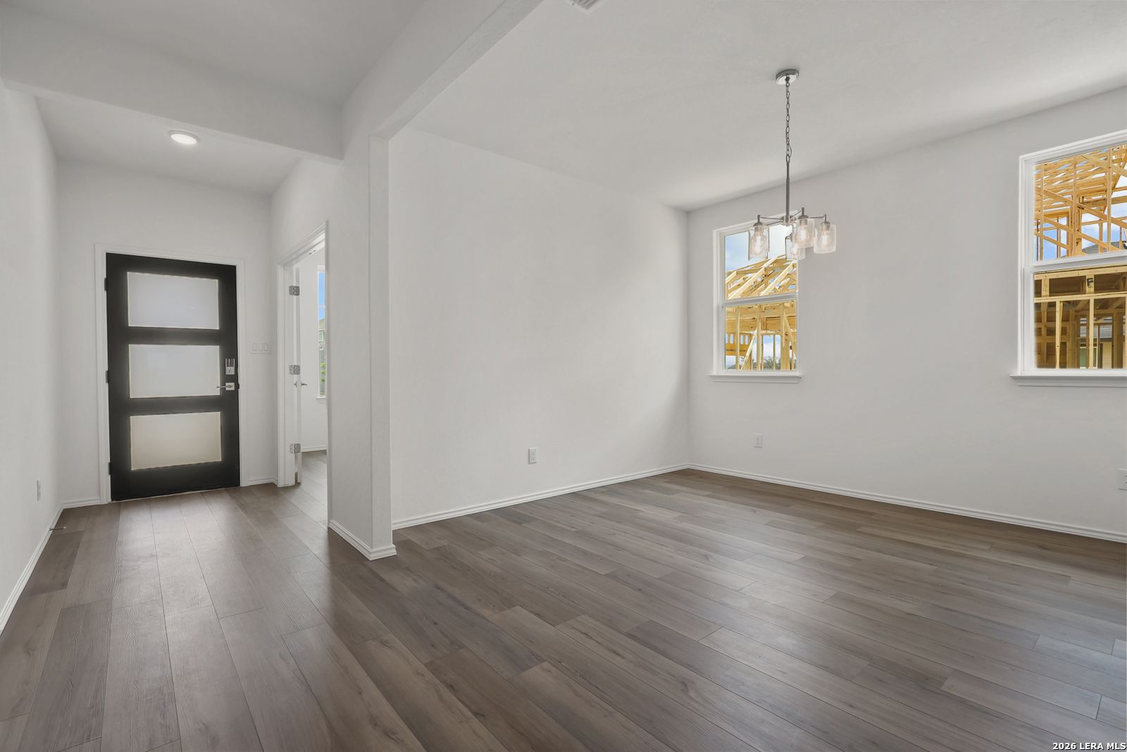 Modern entryway featuring frosted glass black door, white walls, and gray laminate flooring in Davidson Homes The Glenwood E, Elmendorf, Texas