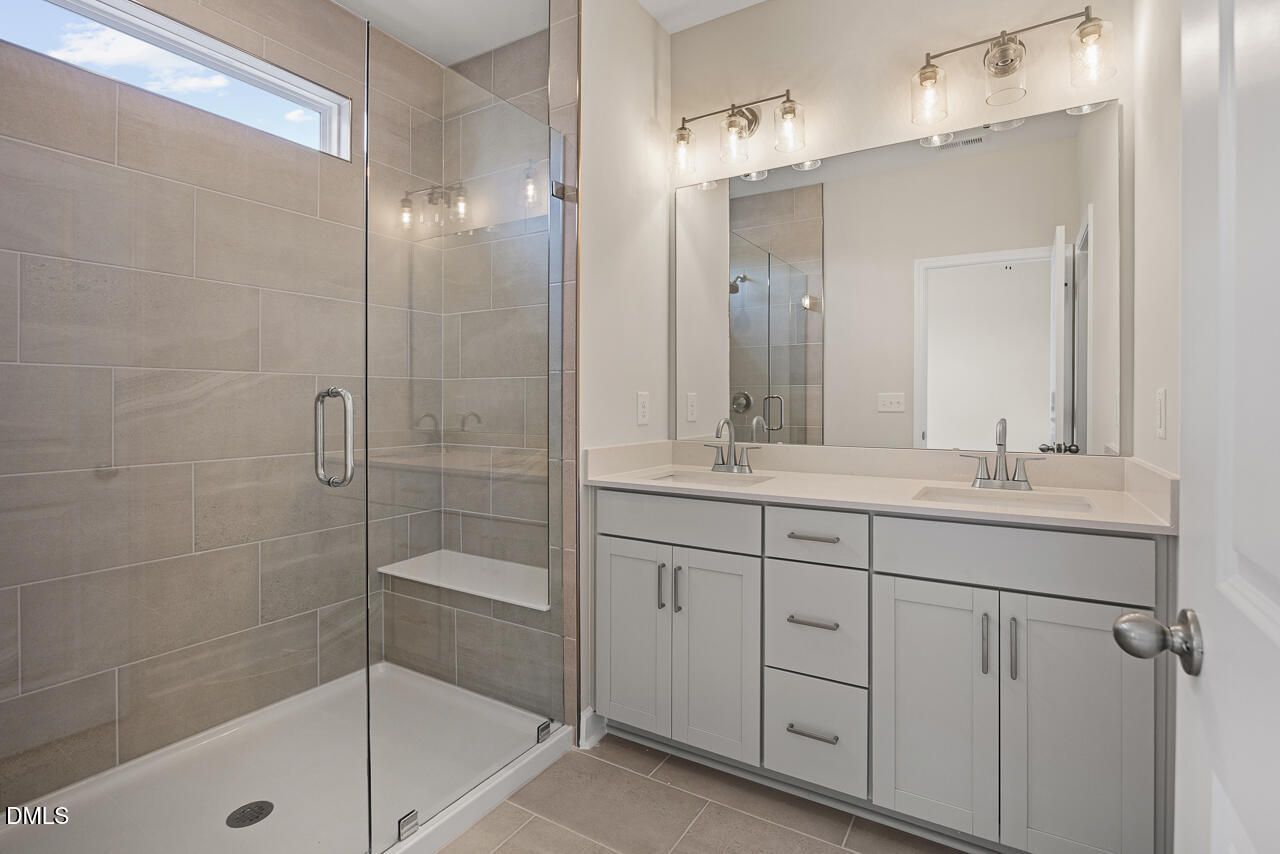 Modern bathroom with dual vanity and tiled walk-in shower in The Alexander C plan at Forestville Yard, Knightdale, NC.