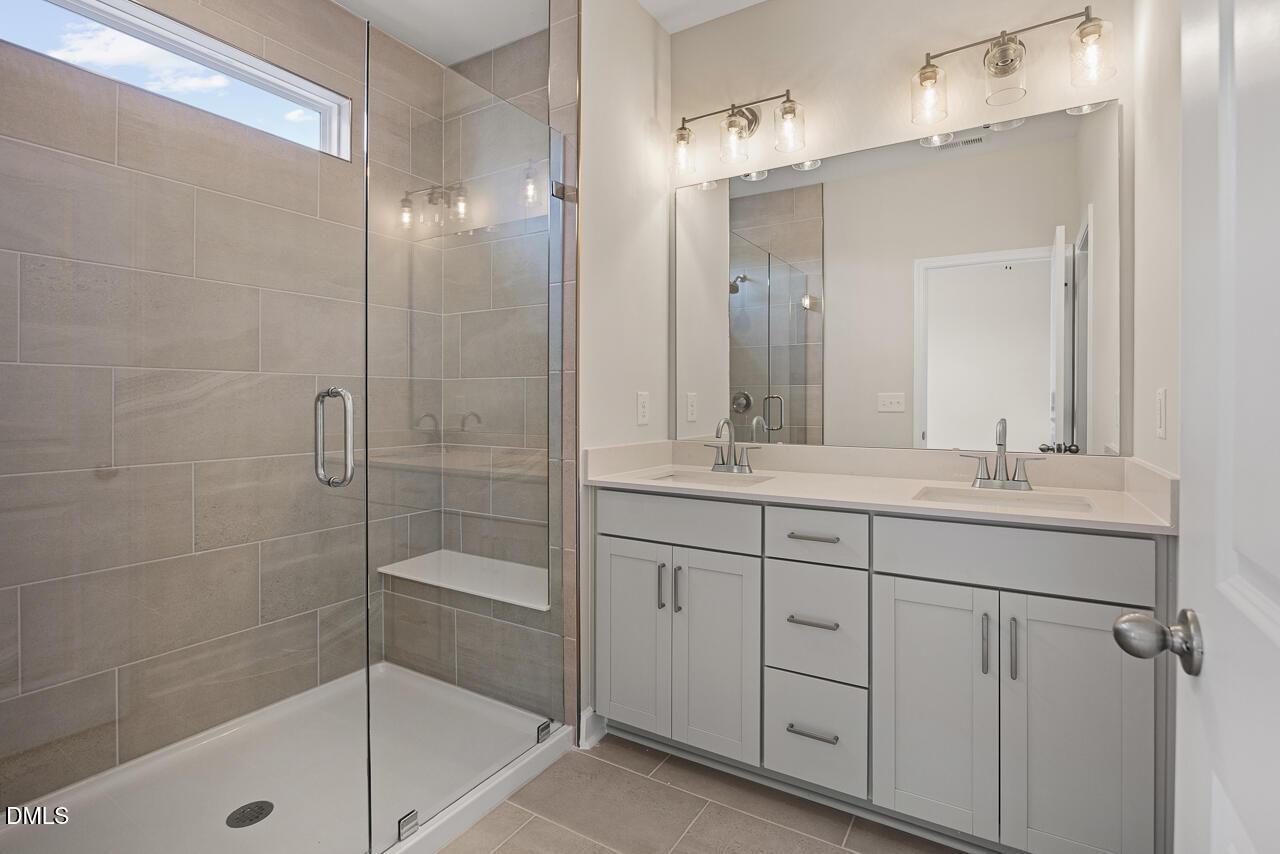 Modern bathroom with dual vanity and tiled walk-in shower in The Alexander C plan at Forestville Yard, Knightdale, NC.