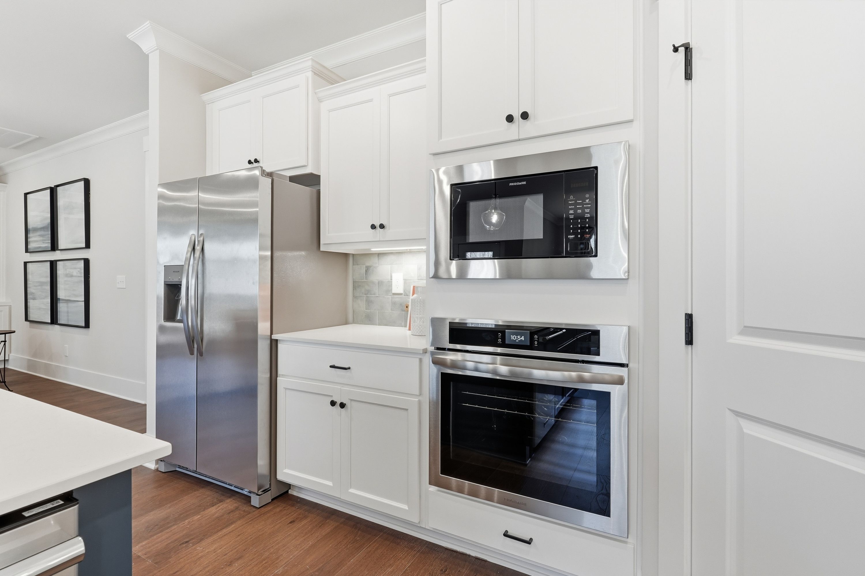 Modern kitchen in Noble Ridge Cullman AL with white shaker cabinets, stainless steel appliances, quartz island, hardwood floors