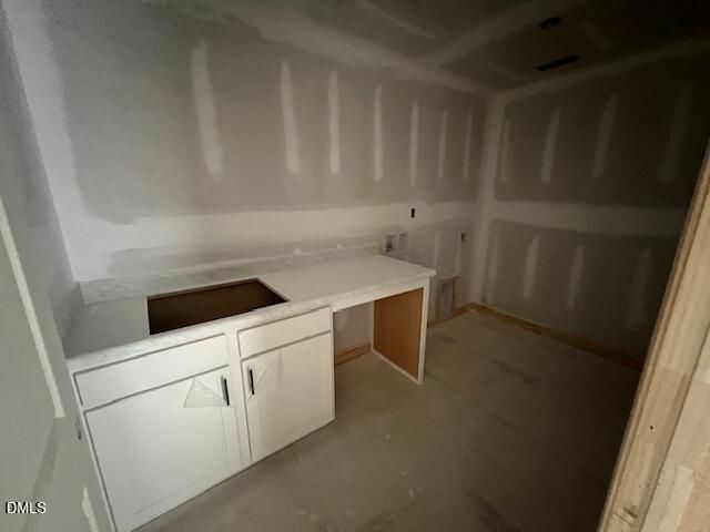 Unfinished laundry room with white cabinets and countertop in The Hickory II C floor plan, Retreat at North Main, Lillington.