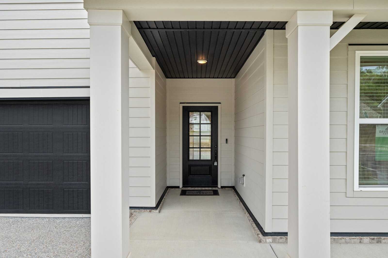 Welcoming covered front porch with columns, black entry door, and 2-car garage on 4-bedroom Davidson Homes Ridgeport in Carellton, Gallatin, Tennessee