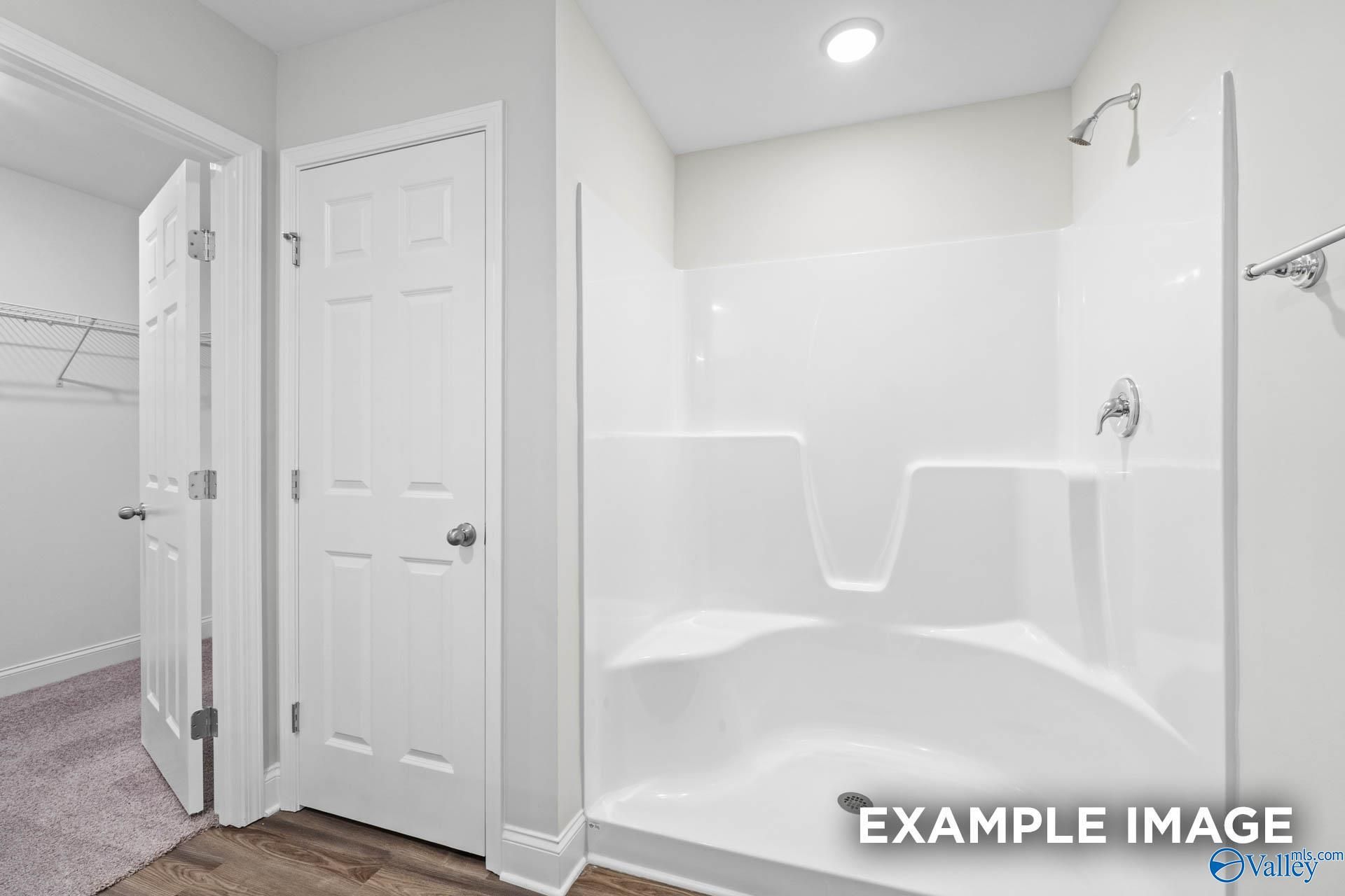 Modern white bathroom with tiled walk-in shower-tub combo and double doors in Davidson Homes The Franklin V, Athens, Alabama