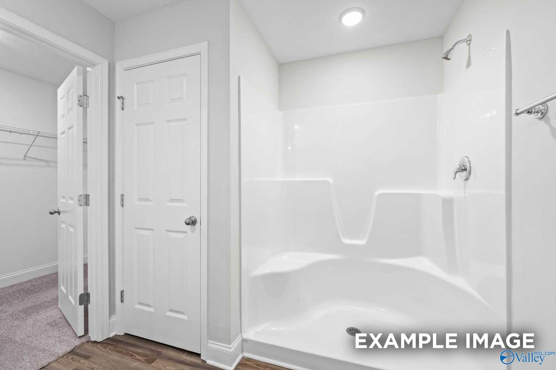 Modern white bathroom with tiled walk-in shower-tub combo and double doors in Davidson Homes The Franklin V, Athens, Alabama