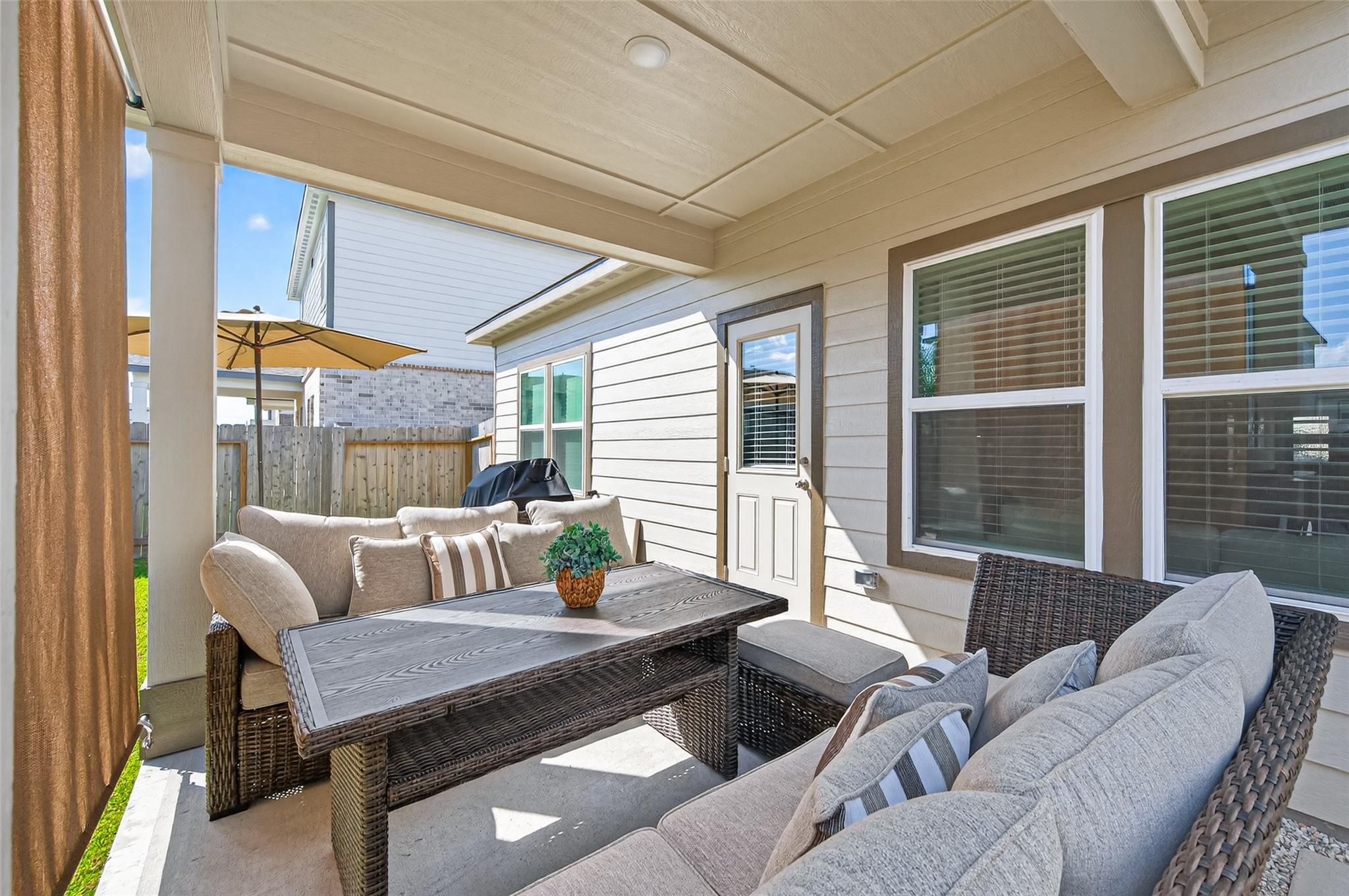 Covered back patio with wicker dining set, gas grill, and cushions in Davidson Homes The Brazos E, Lakes at Black Oak, Magnolia, Texas