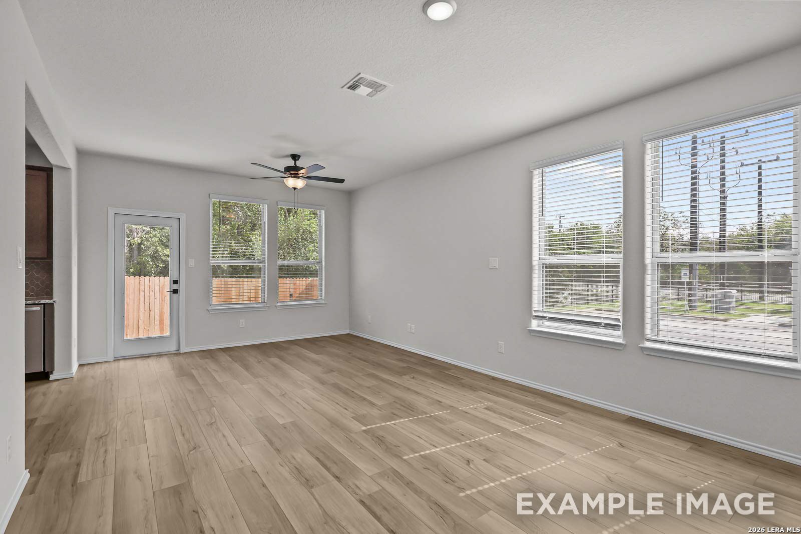 Bright, open-concept living area with wood-style flooring in The Florence D floor plan by Davidson Homes in San Antonio.