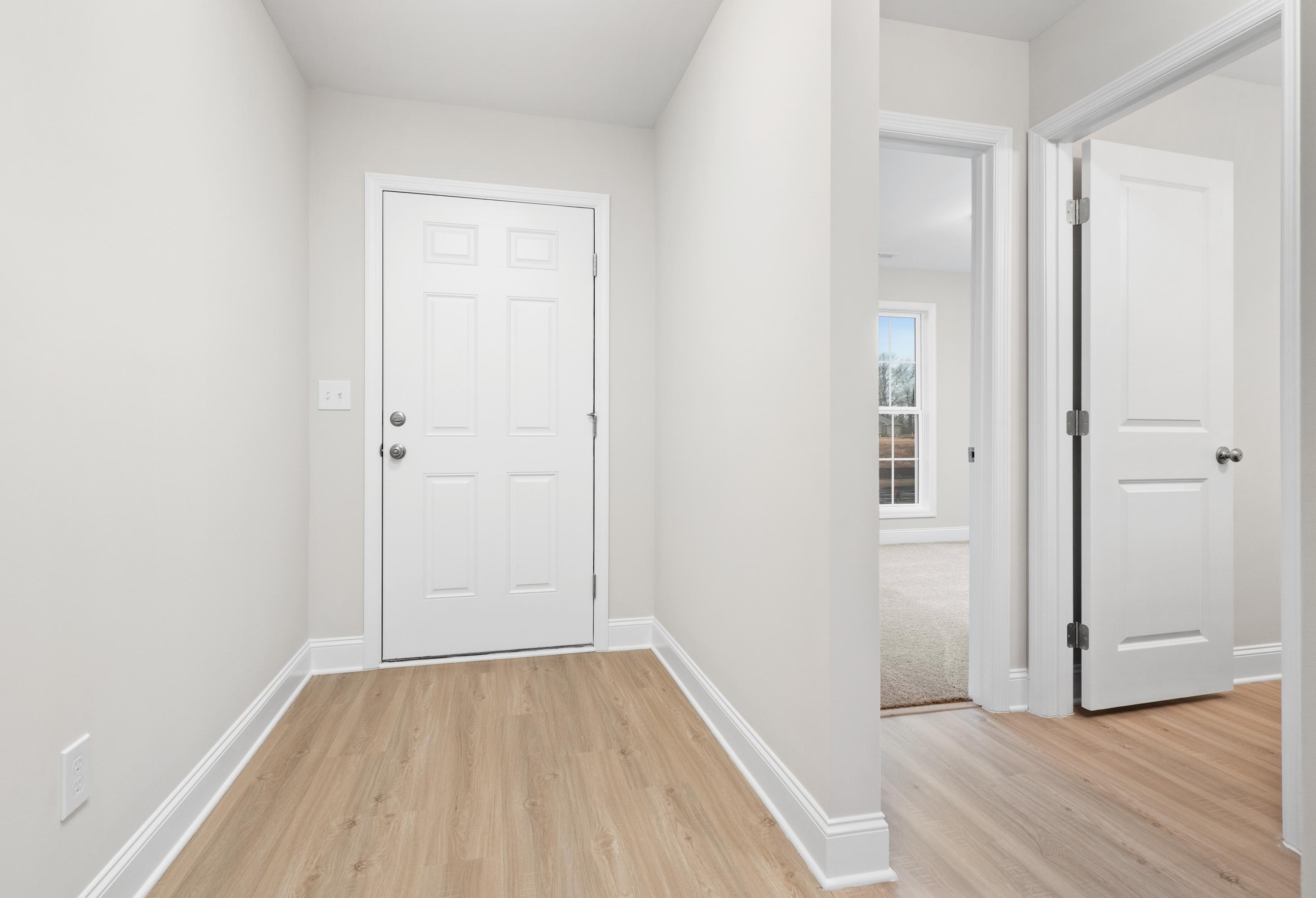 Spacious entryway hallway in The Asheville 3-bedroom home design featuring white doors, light wood floors, and neutral walls