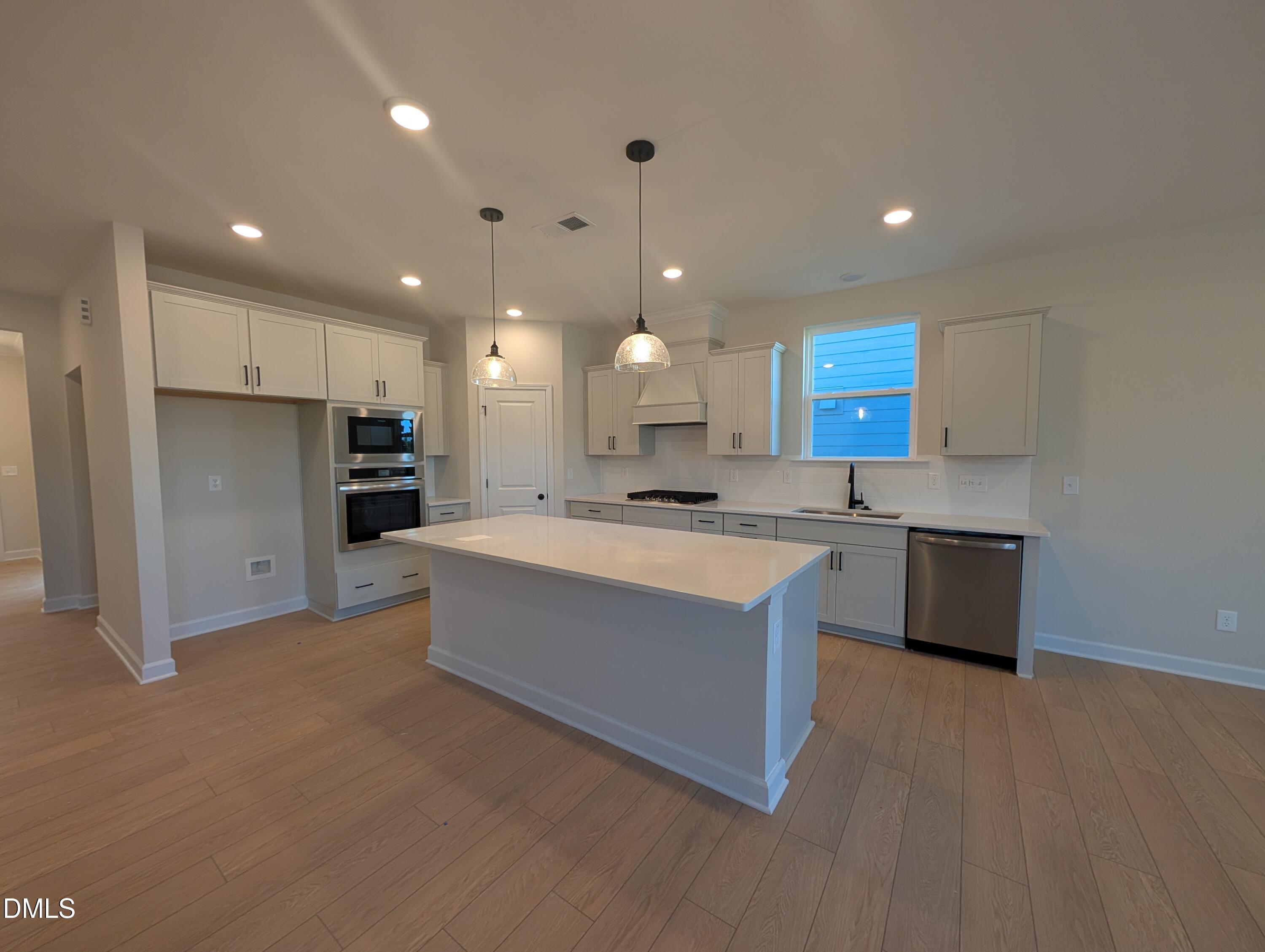 Modern kitchen with large island, white cabinetry, and stainless appliances in Davidson Homes Ashport M plan, Wendell Ridge, NC