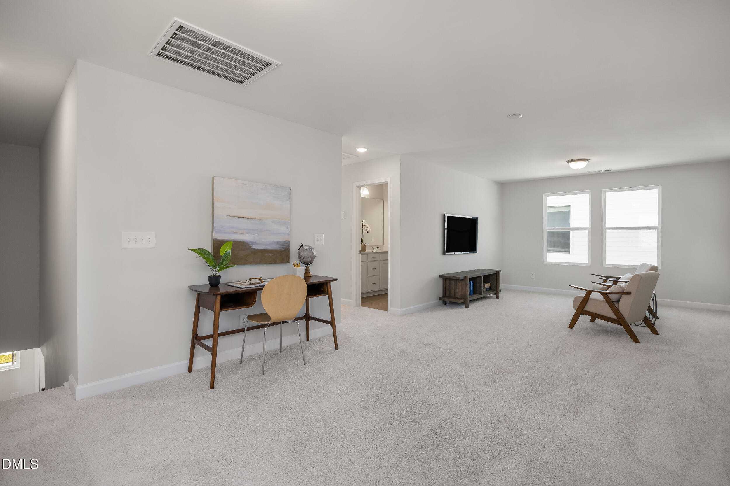 Upstairs home office with wooden desk, potted plant, mounted TV, and bathroom access in Davidson Homes Preston C, Lillington NC