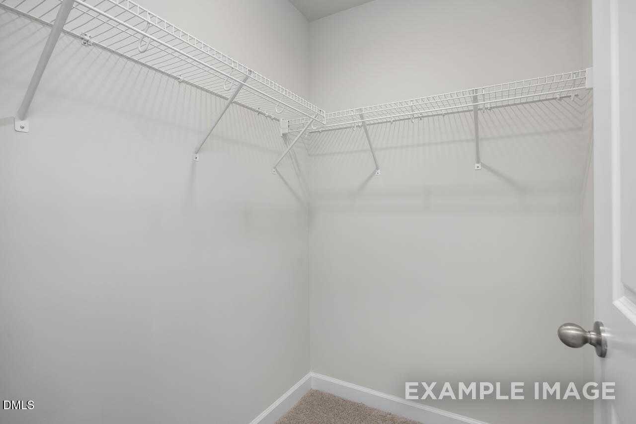 Spacious walk-in closet with white wire shelving and hanging rods in Davidson Homes The Adalynn A, Lillington, NC